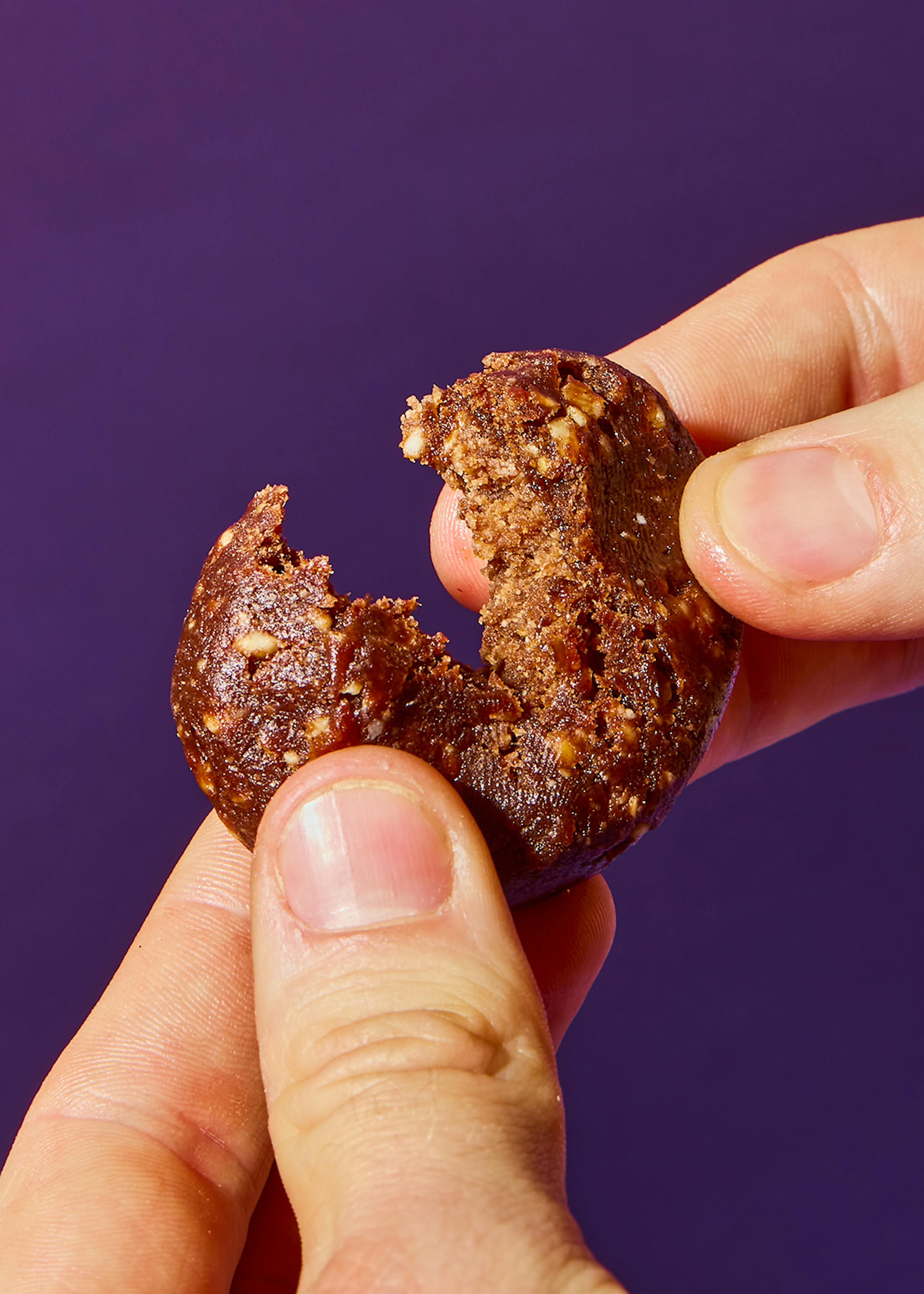 a person holding a cookie with a bite taken out of it