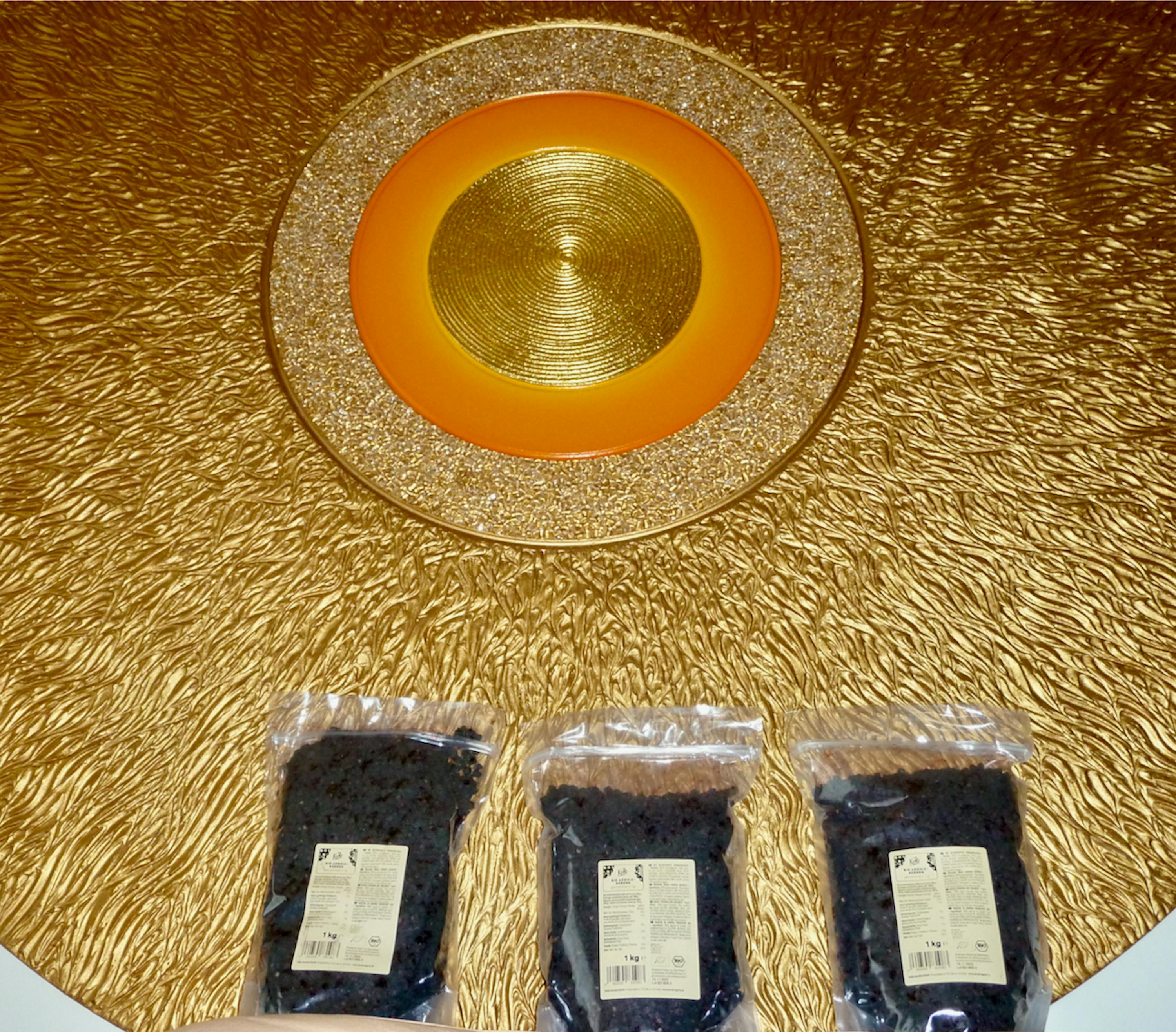 trois sacs de raisins sont posés sur une surface dorée