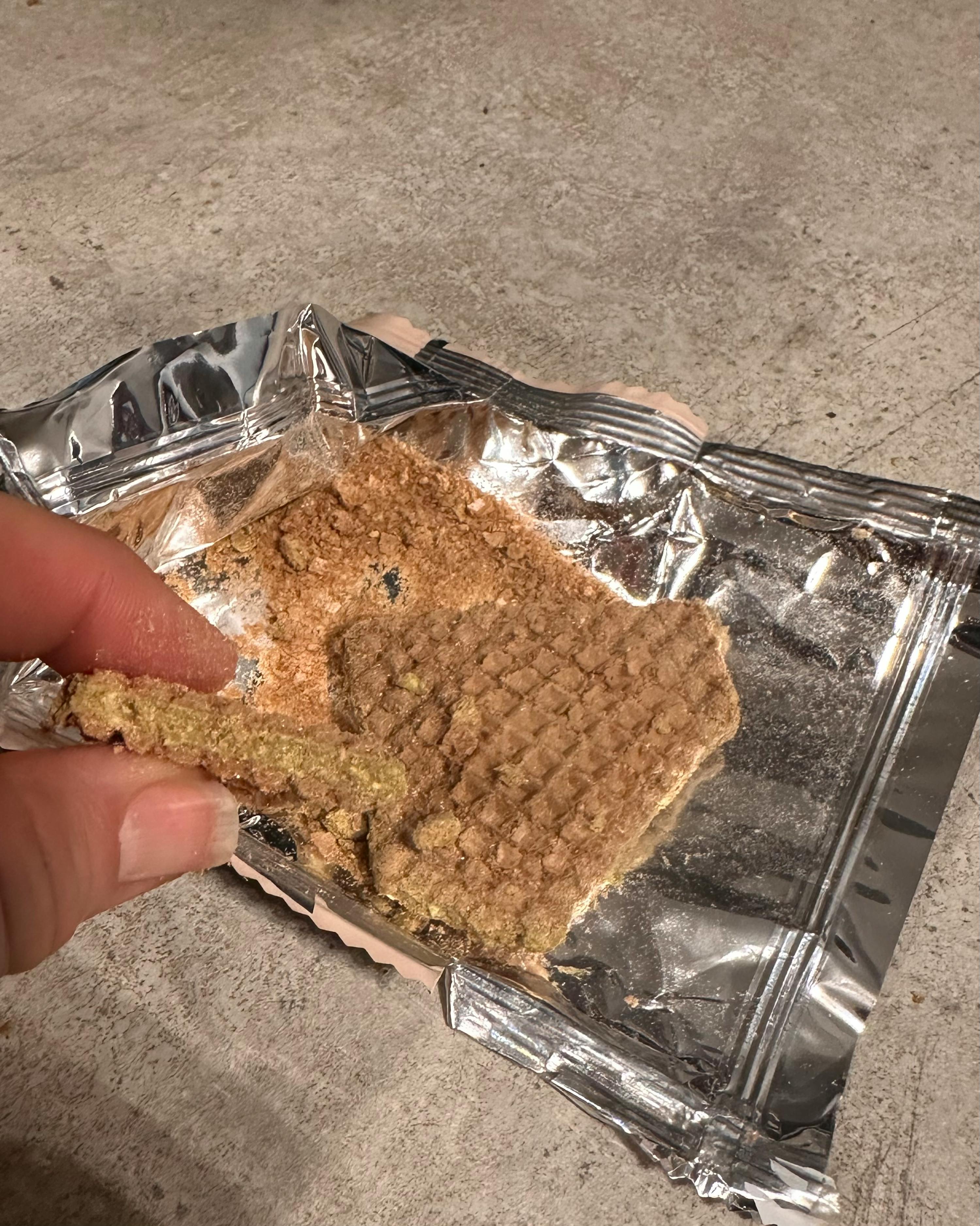 a person is holding a piece of food in aluminum foil
