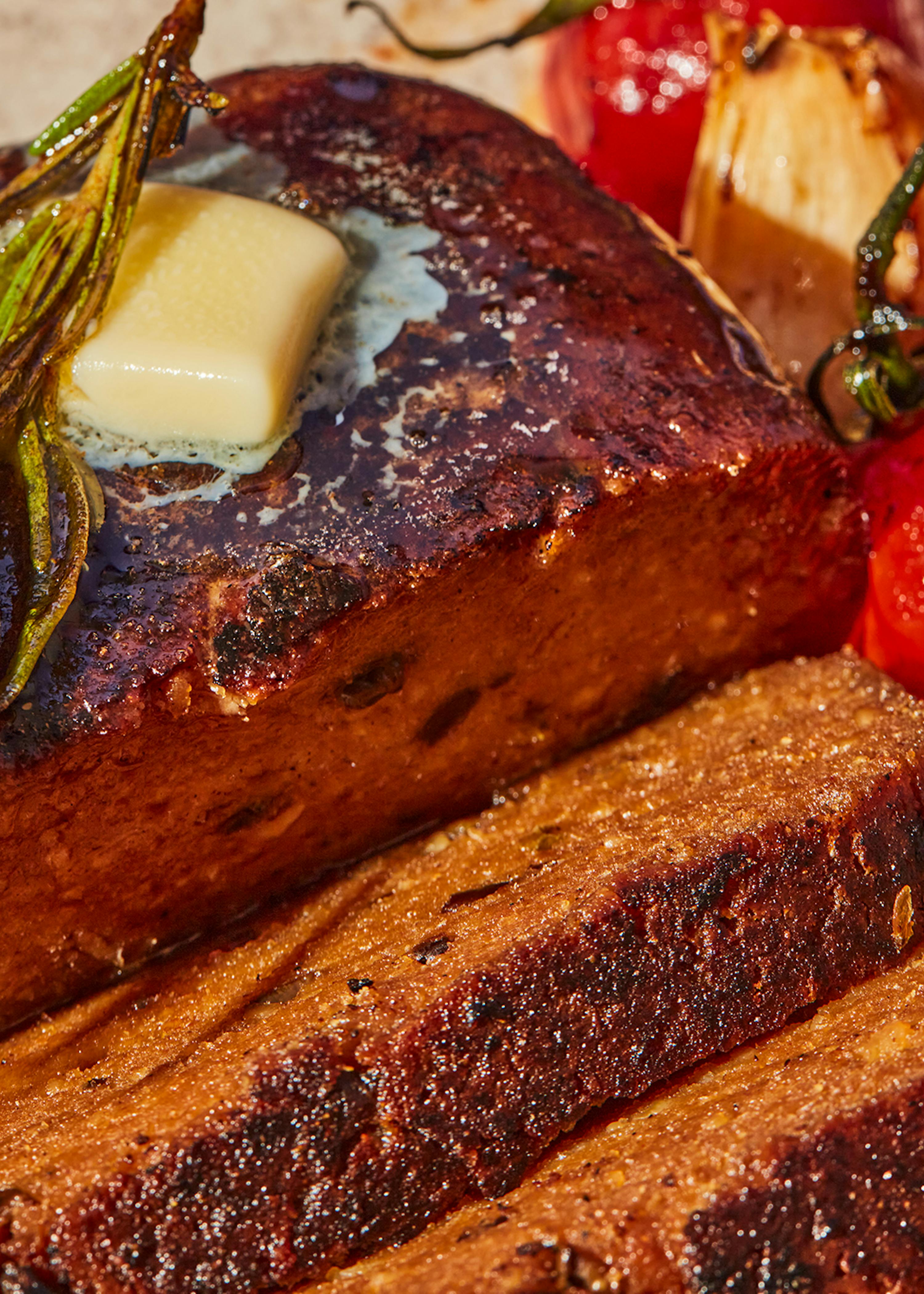 ein Stück Fleisch mit Butter und Tomaten darauf