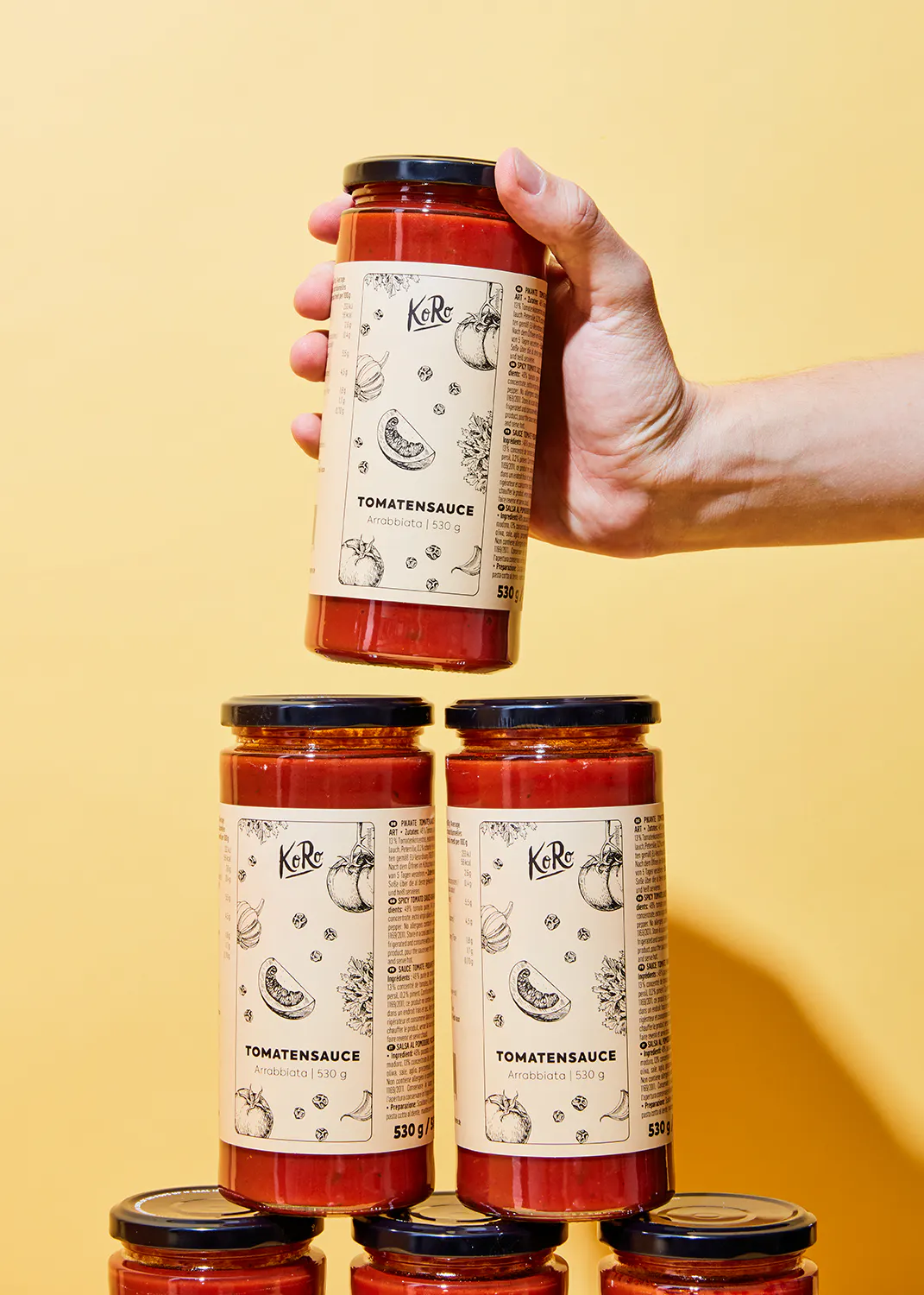 a hand is holding a jar of tomato sauce with a label that says tomatensauce