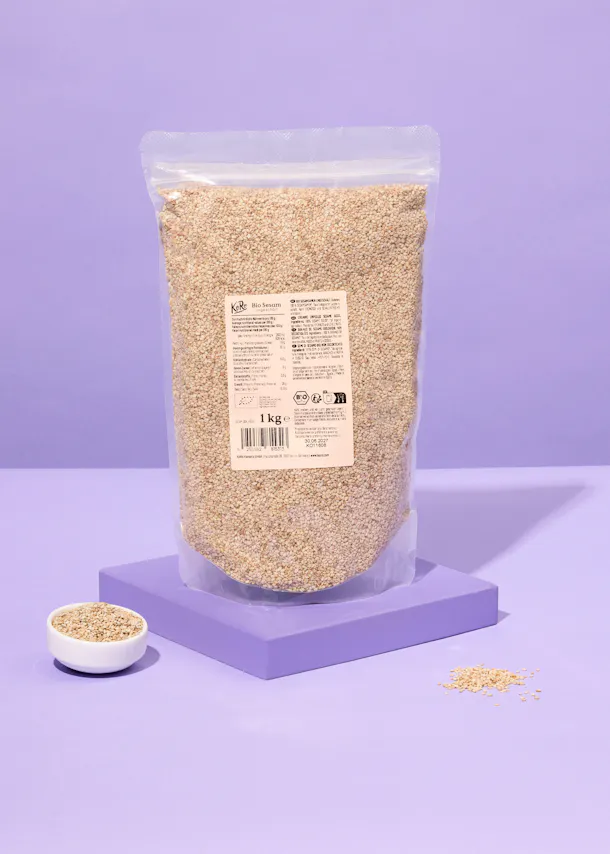 a bag of sesame seeds is on a purple surface