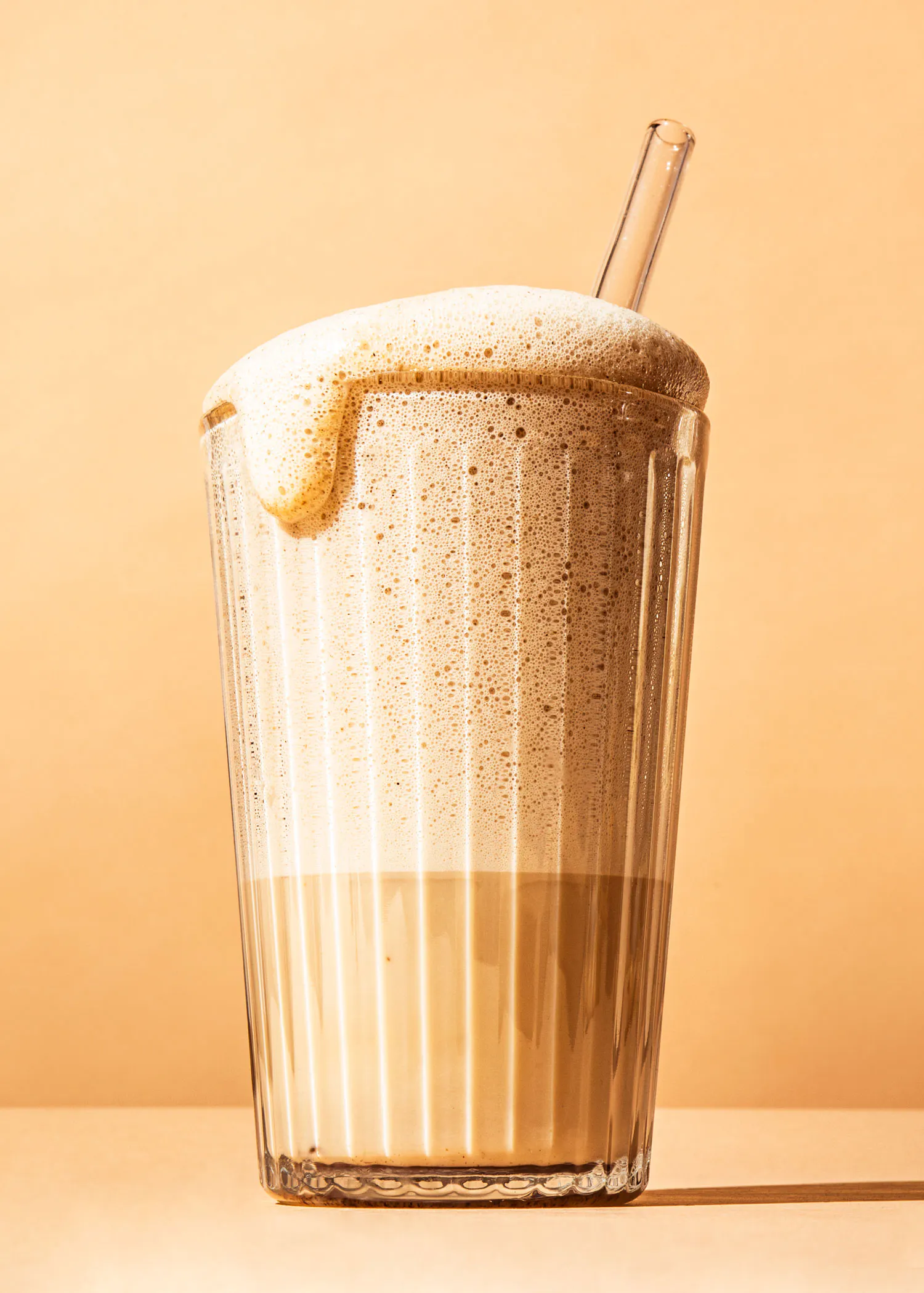 un verre de cappuccino avec une paille en verre