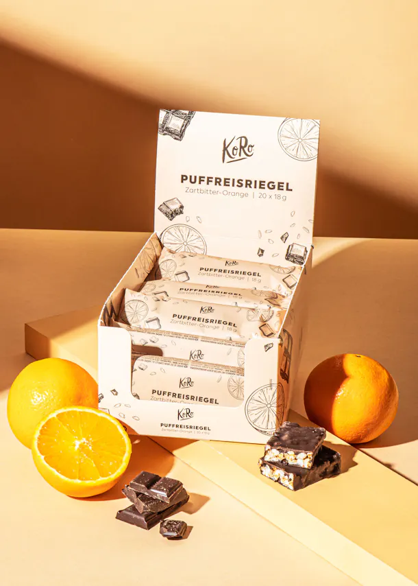 une boîte avec des barres de chocolat et des oranges à côté