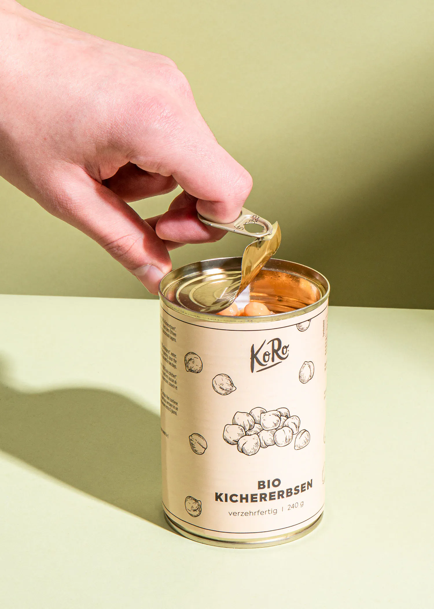 une personne ouvre une boîte de kichererbsen bio avec une cuillère