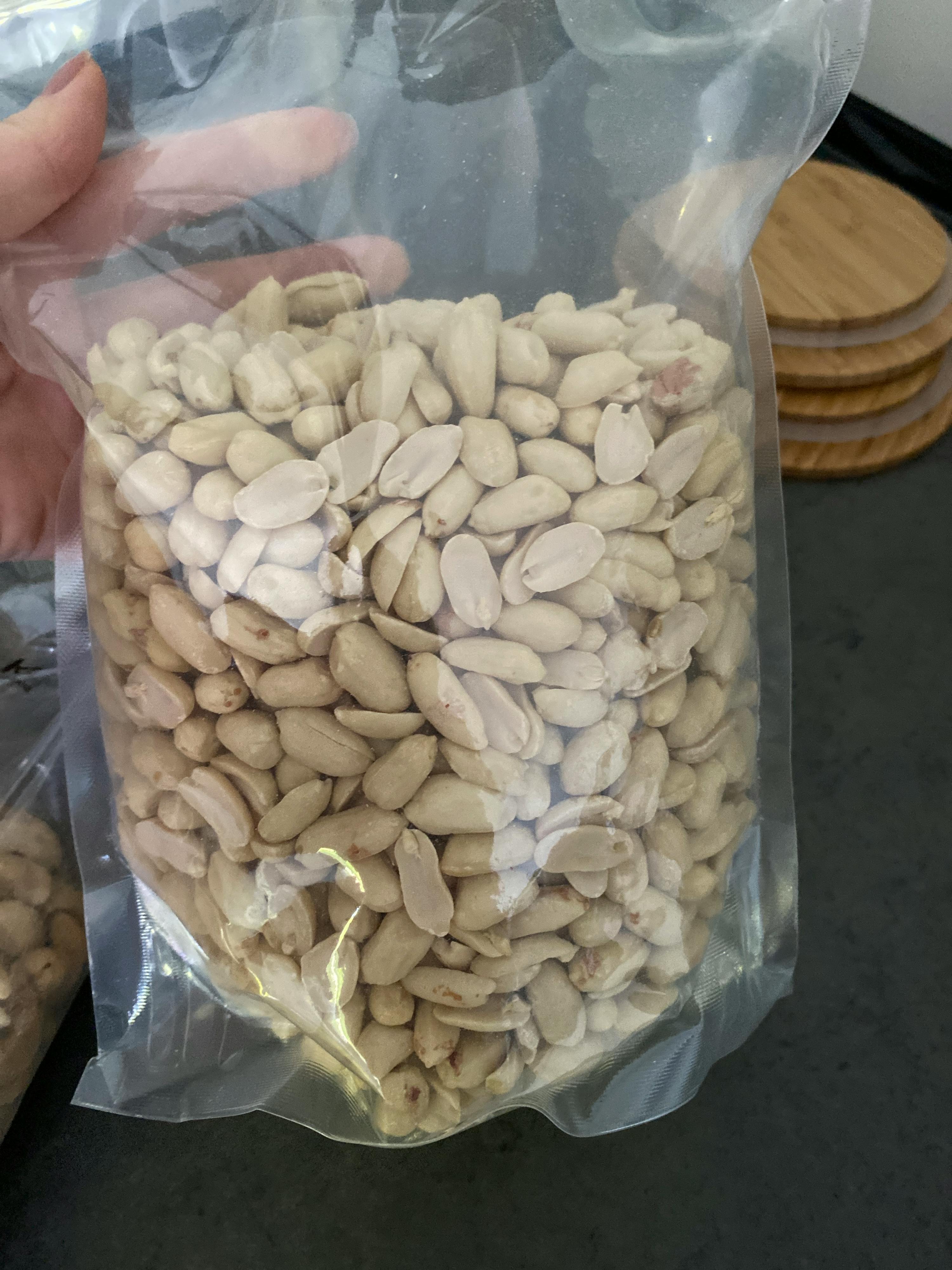 eine Person hält eine Plastiktüte mit Erdnüssen in der Hand