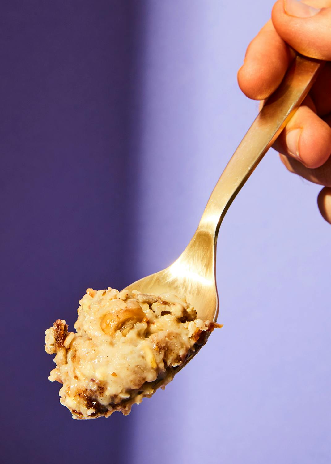 una persona tiene in mano una cucchiaio di cibo su sfondo viola