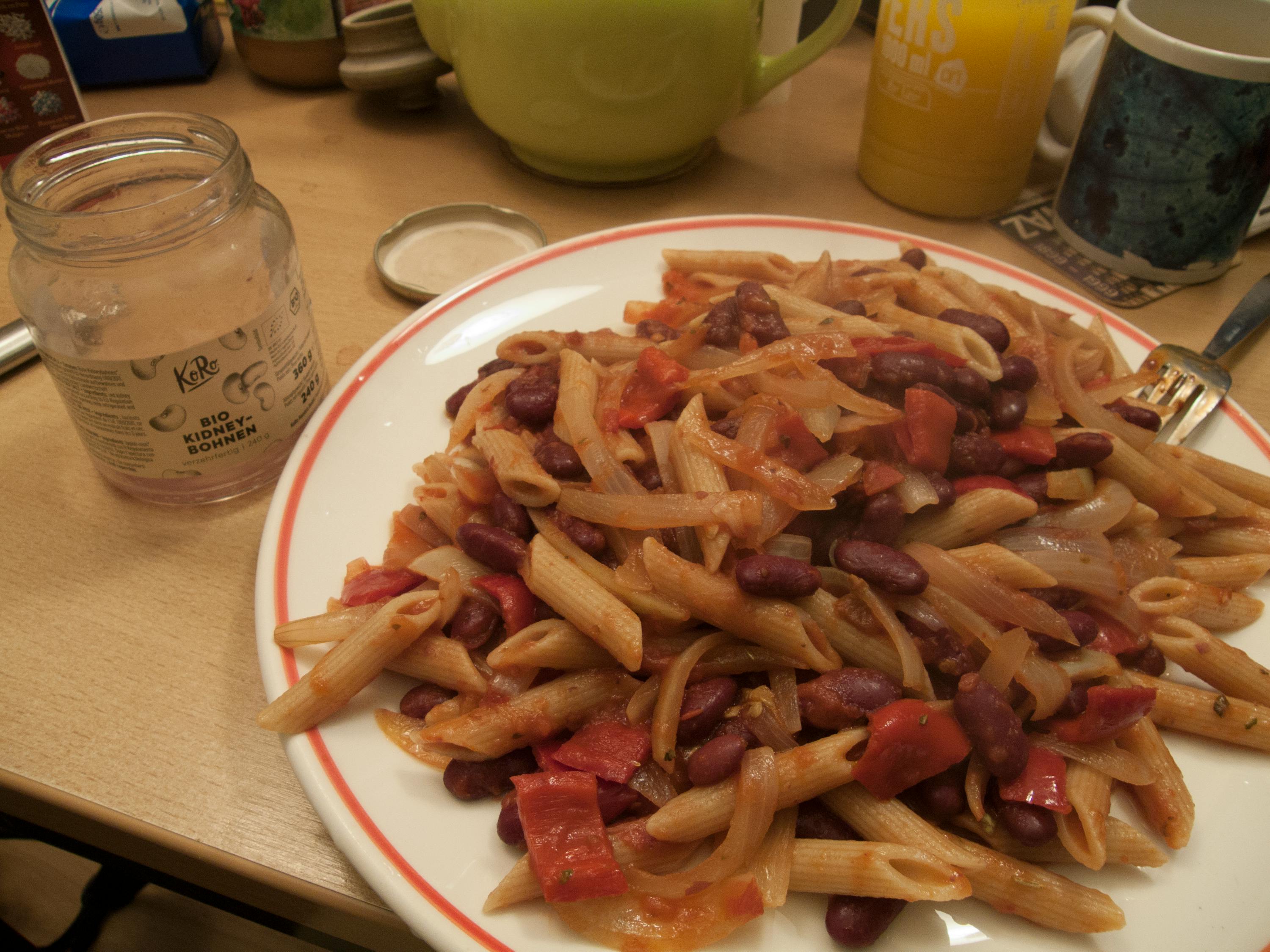 une assiette de pâtes avec des haricots rouges et une bouteille de kale