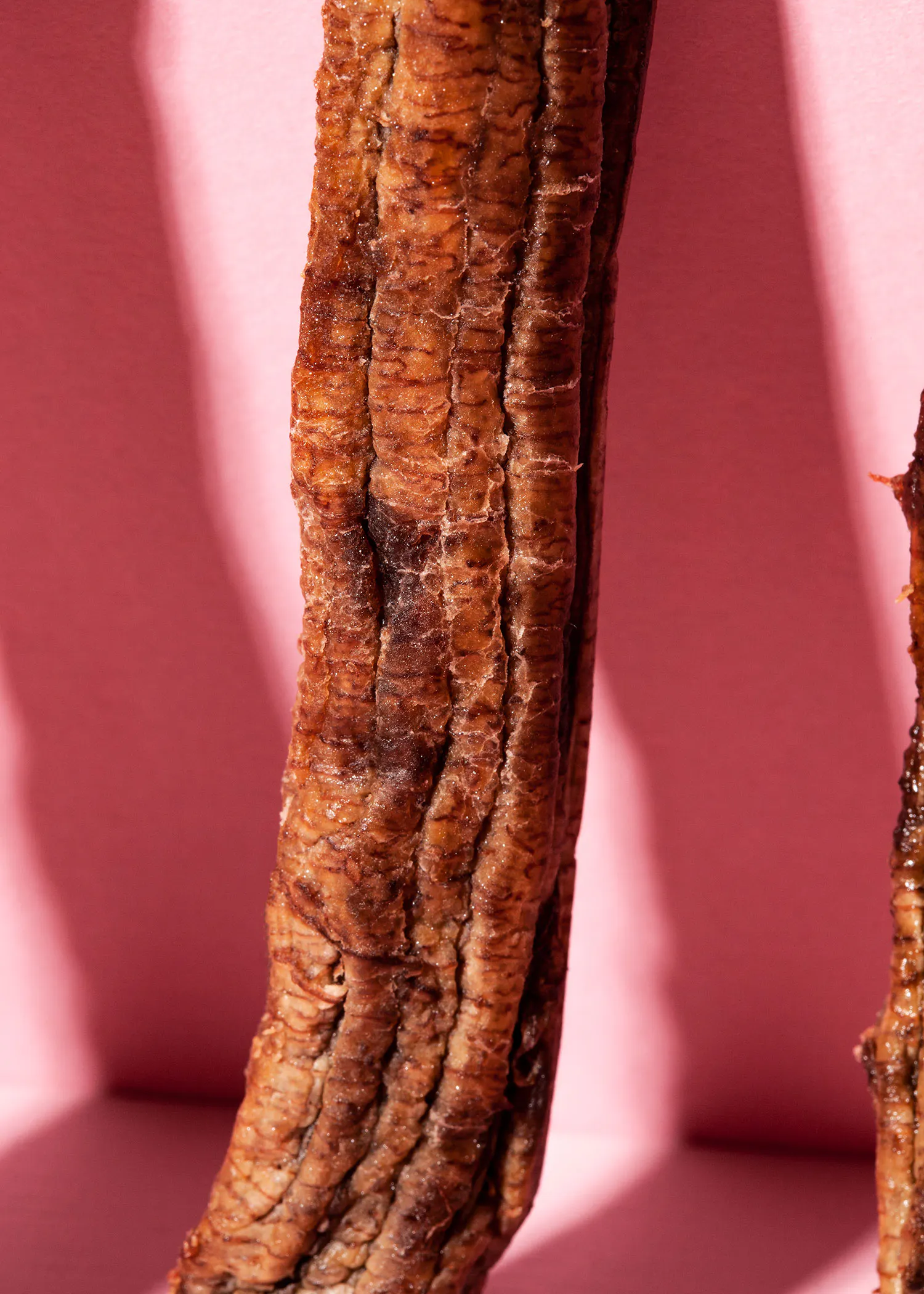un gros plan d' une banane séchée sur fond rose