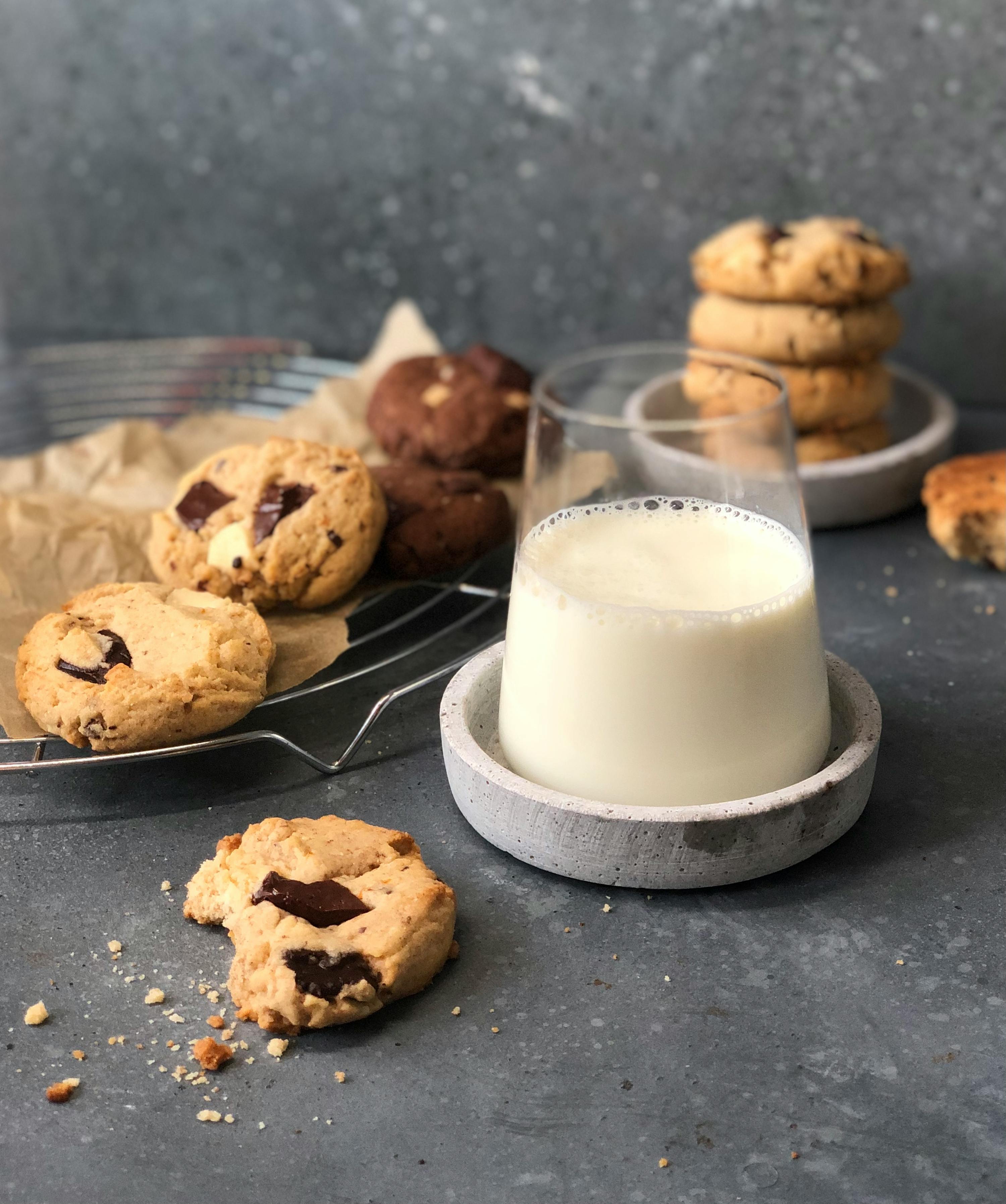 a glass of milk sits next to a tray of cookies