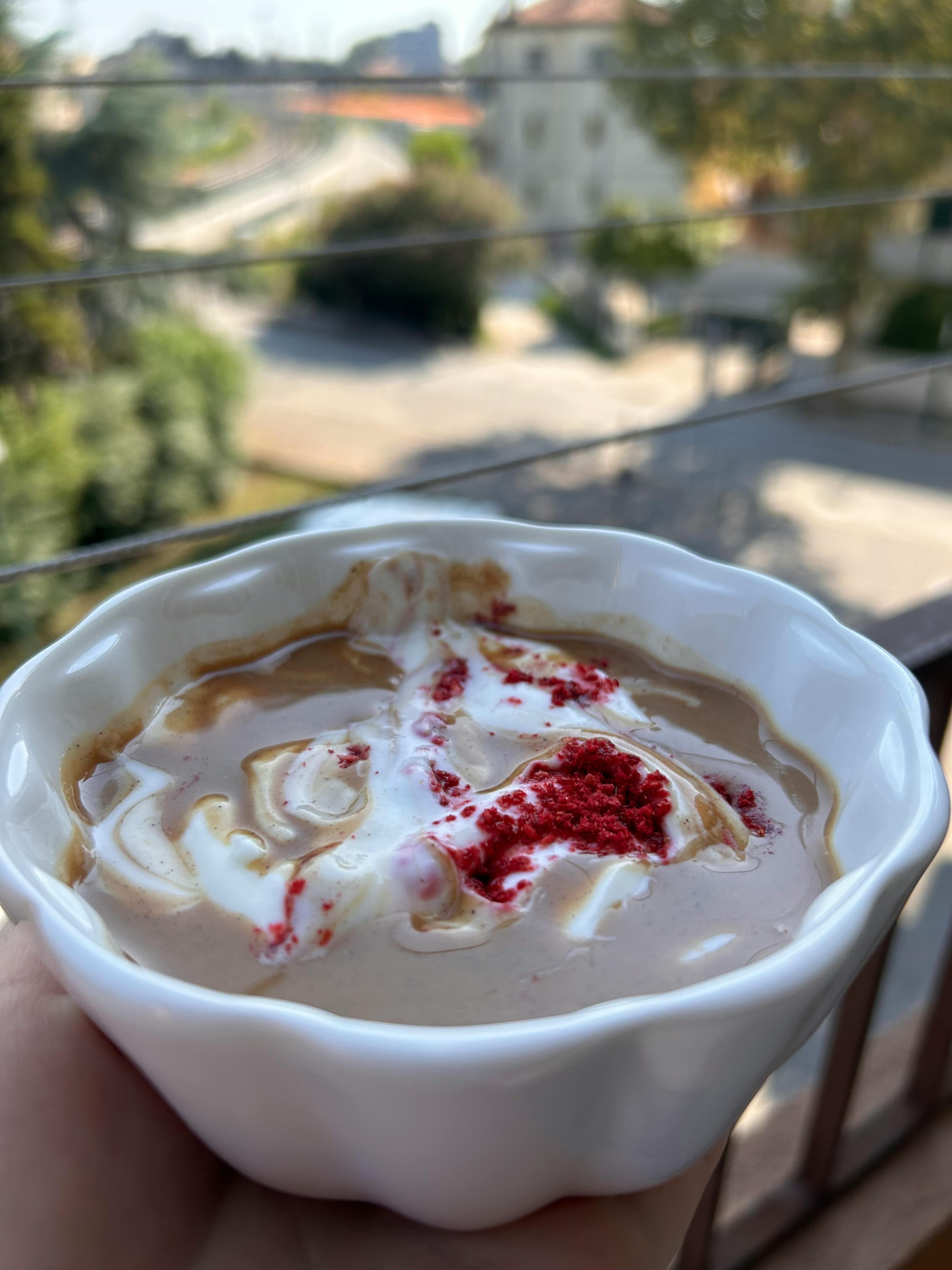 eine Person hält eine weiße Schüssel mit einem Dessert in der Hand