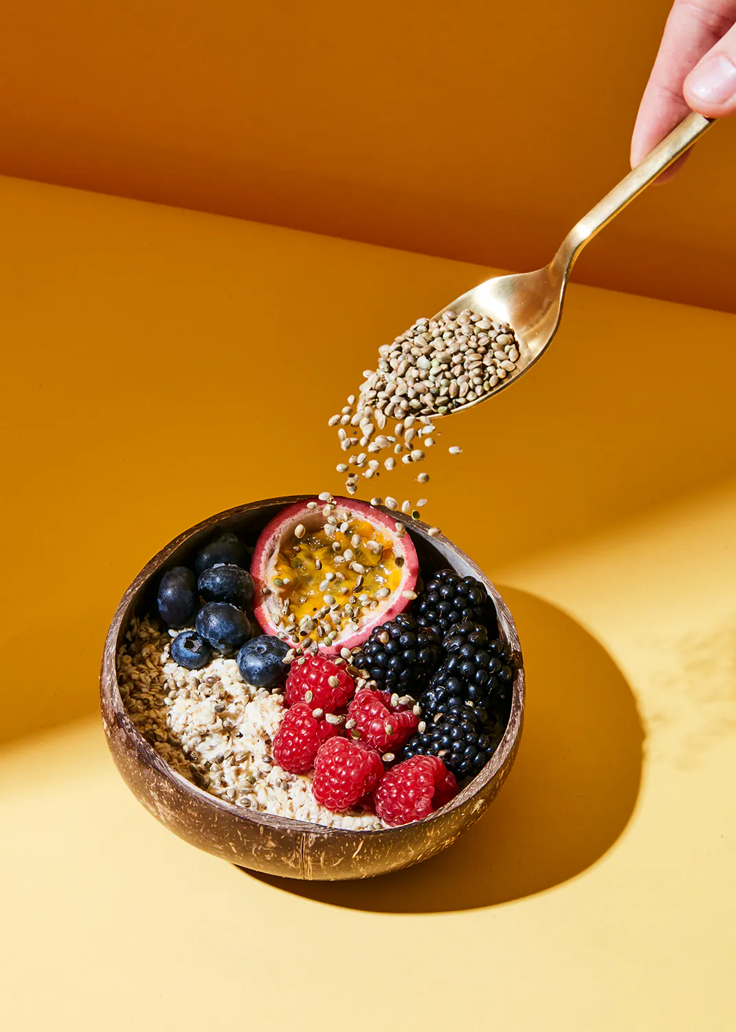 une personne verse des graines de chia dans un bol rempli d' avoine et de fruits