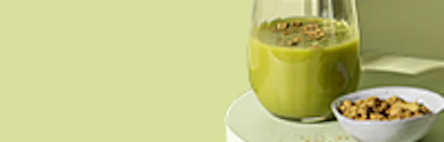 ein grüner smoothie in einem glas mit streuseln und eine schale mit streuseln daneben.