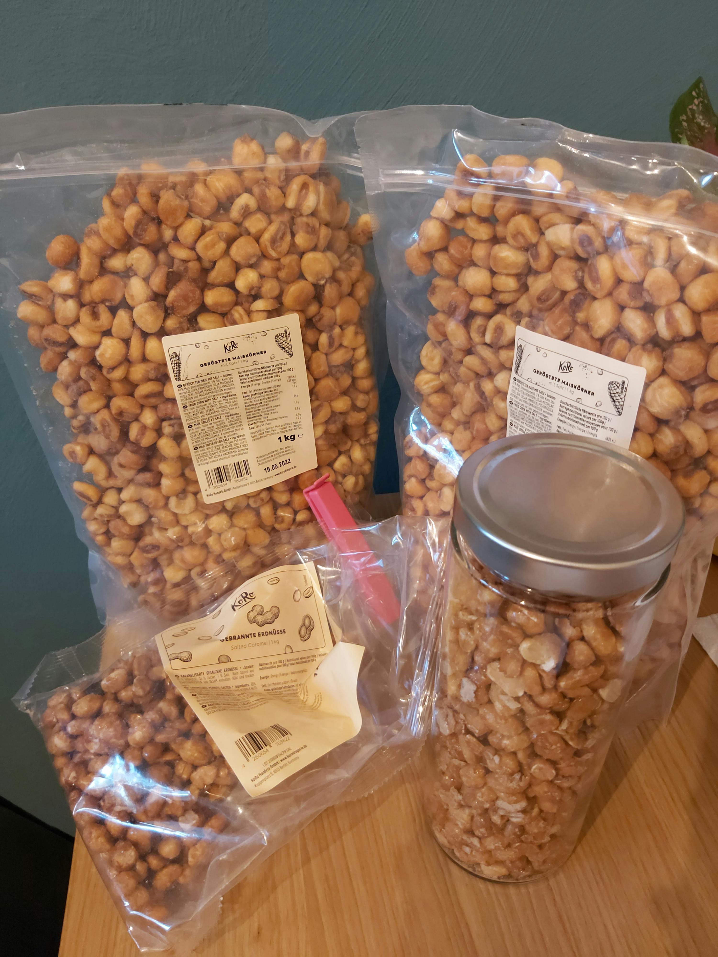 a jar of peanuts sits on a table next to a bag of peanuts