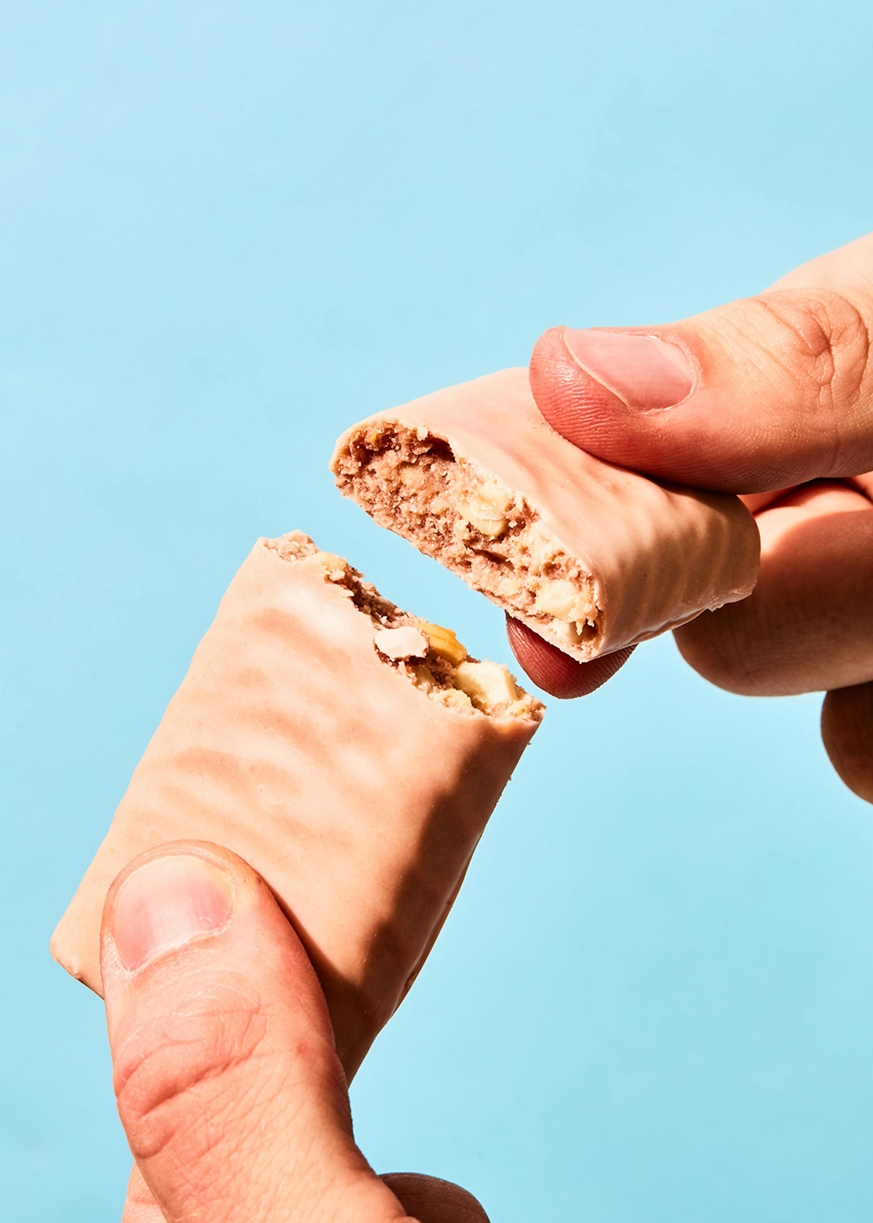 a person is holding a candy bar with a bite taken out of it