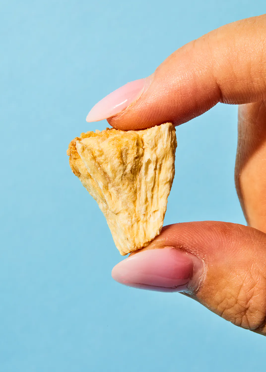 une femme avec des ongles roses tient un morceau de nourriture