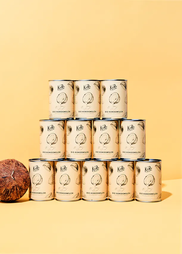 a stack of cans of ke re coconut milk on a yellow background