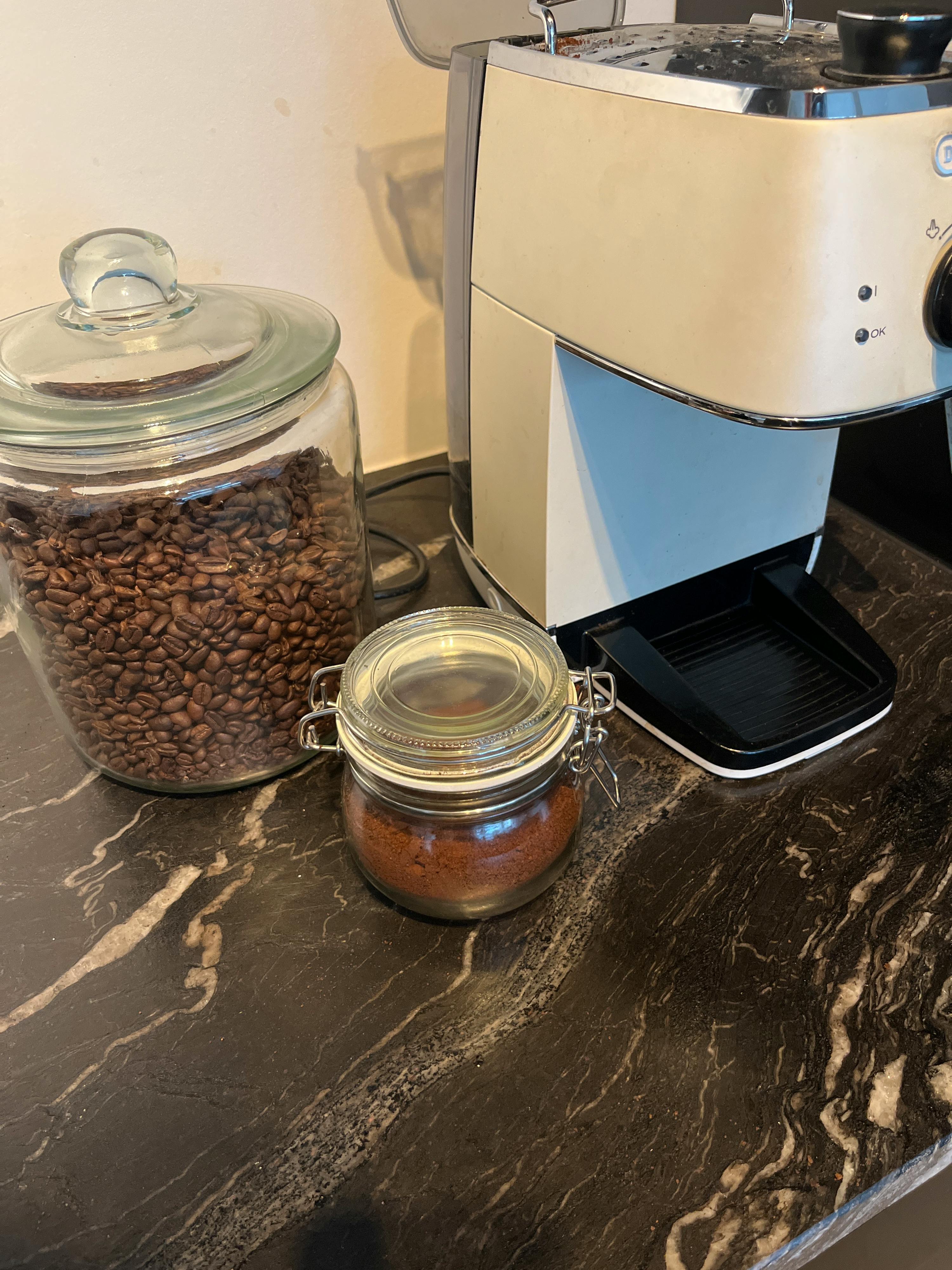 Eine Kaffeemaschine steht neben einem Glasgefäß mit Kaffeebohnen