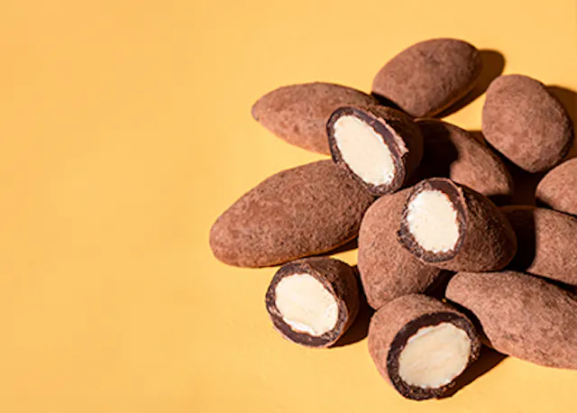 ein Haufen Schokoladen-Mandeln auf gelbem Hintergrund