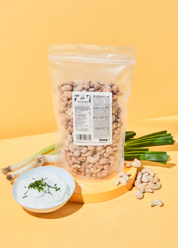 un sac de noix de cajou est assis à côté d' un bol de sauce