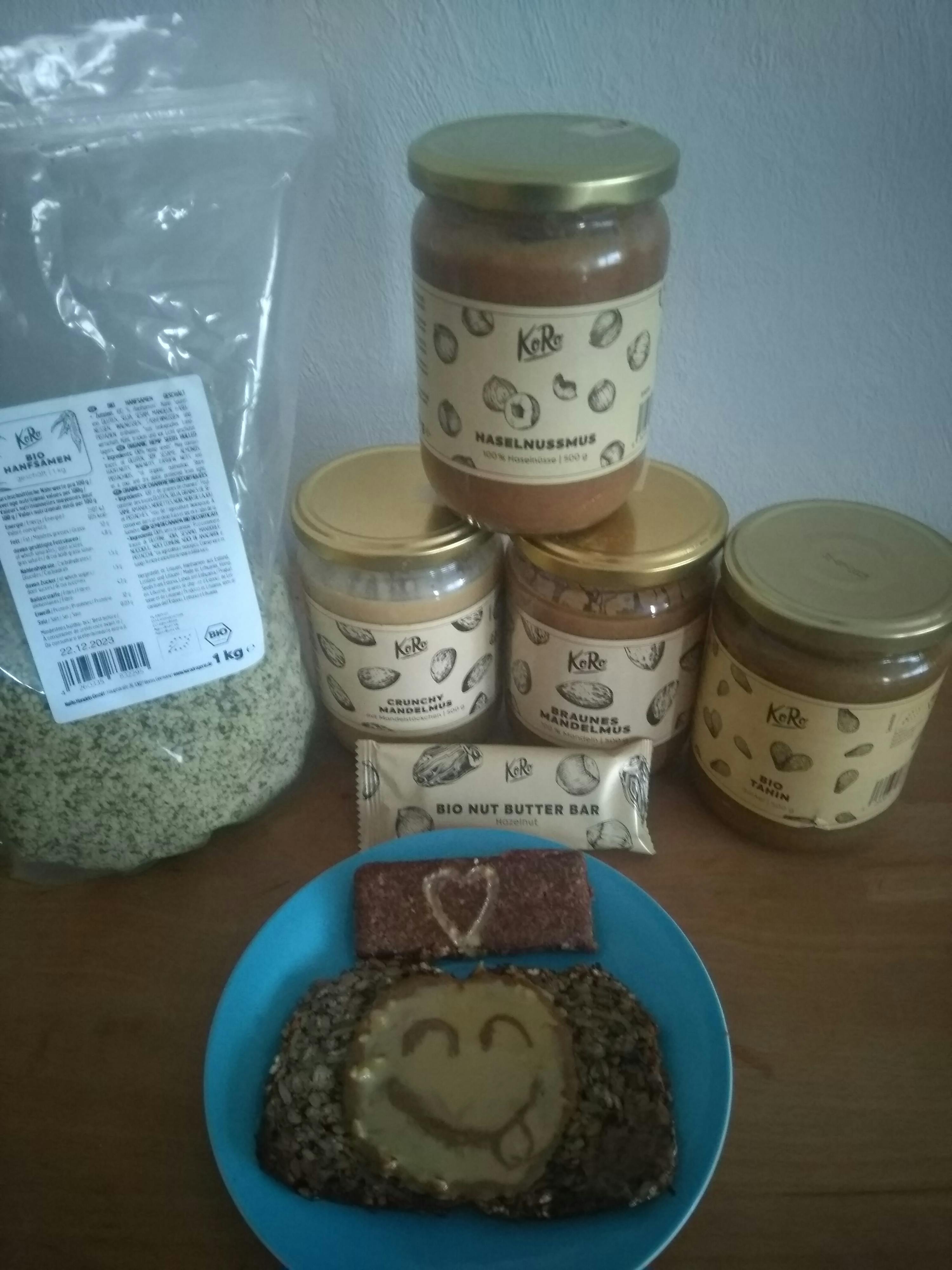 ein blauer Teller mit einem Smiley auf einem Stück Brot neben einem Haselnussbutter-Bar