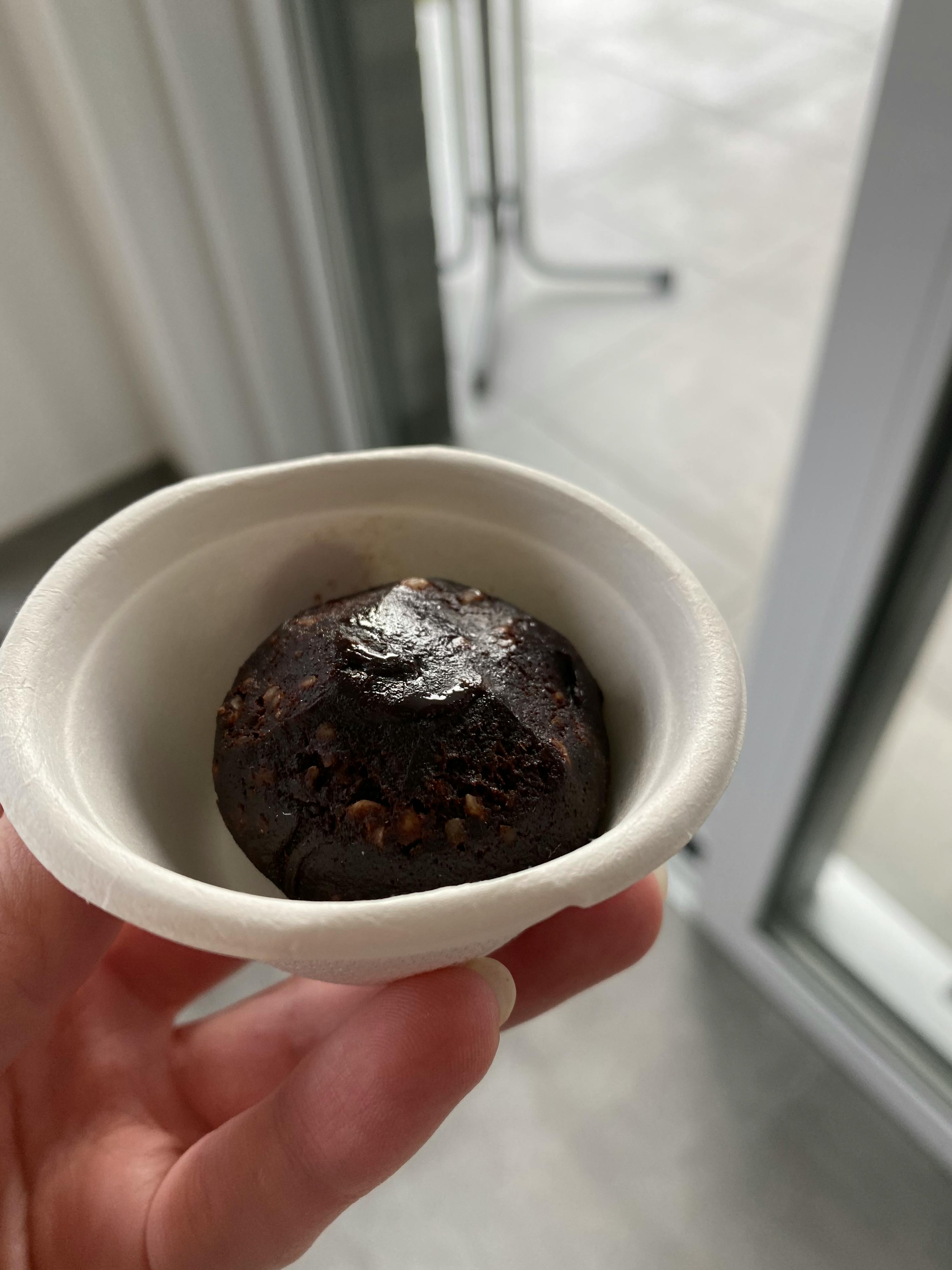 una persona tiene in mano una ciotola di carta con un pezzo di cioccolato dentro
