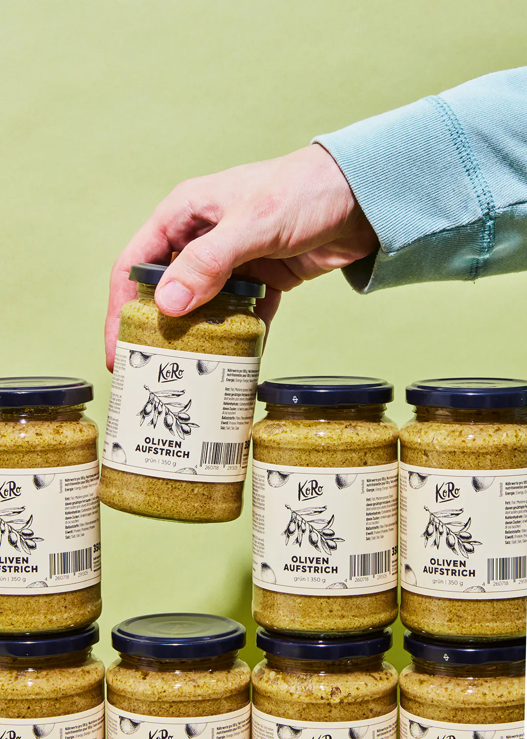 eine Person hält ein Glas Oliven aufstrich in der Hand