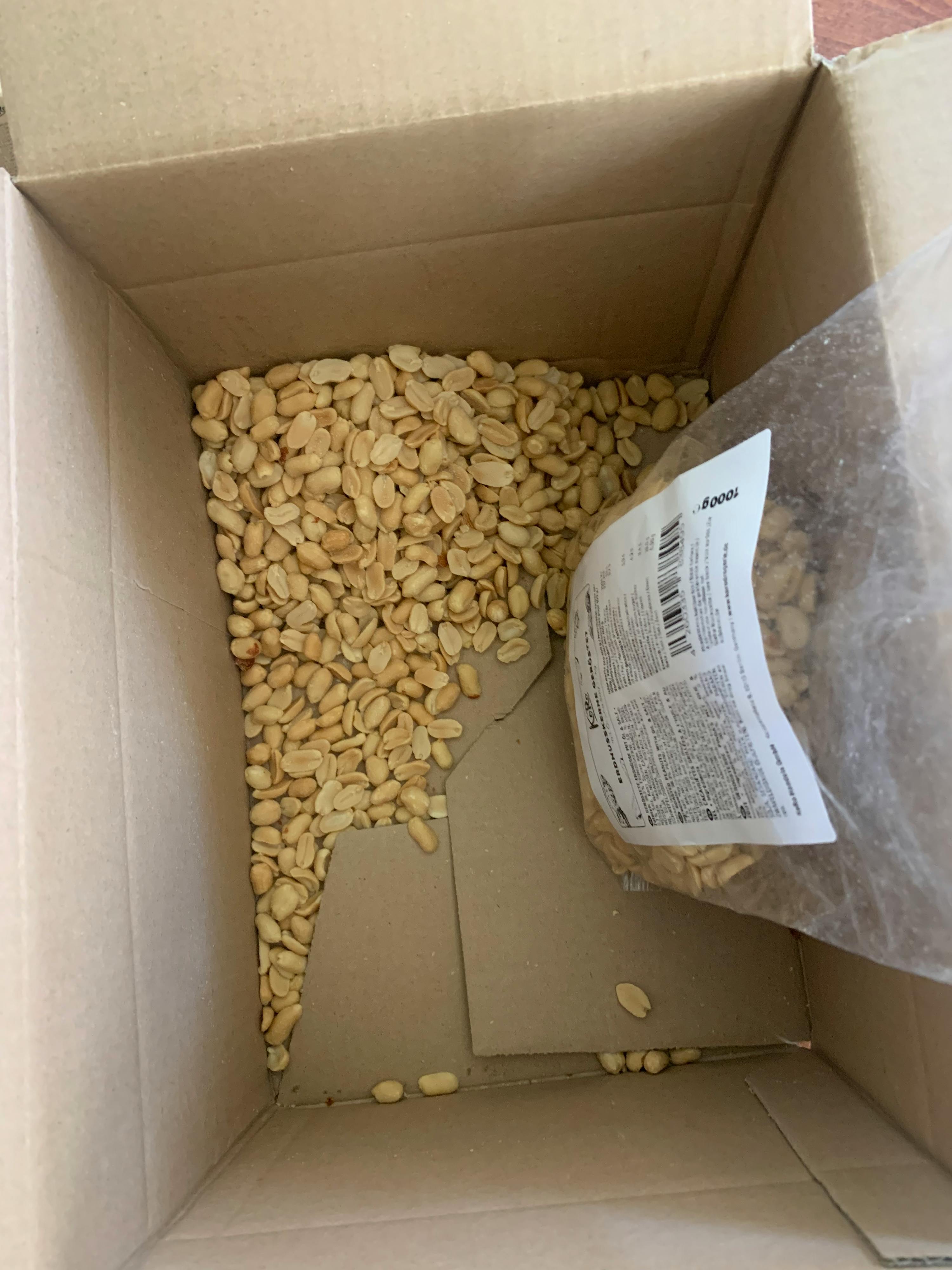 una scatola di cartone piena di arachidi con un sacchetto di arachidi sopra
