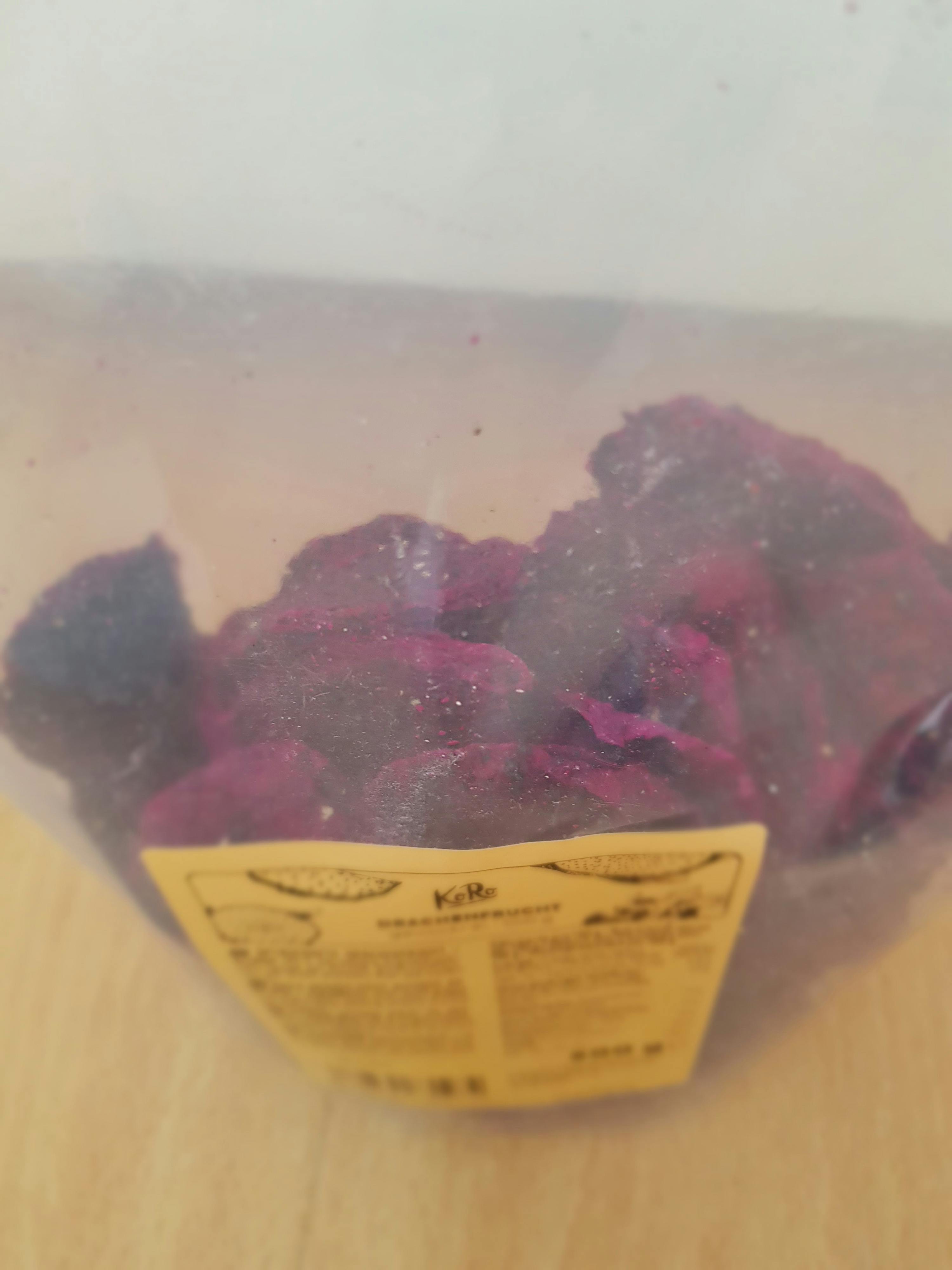 a plastic container filled with purple fruit and a yellow label that says kalle
