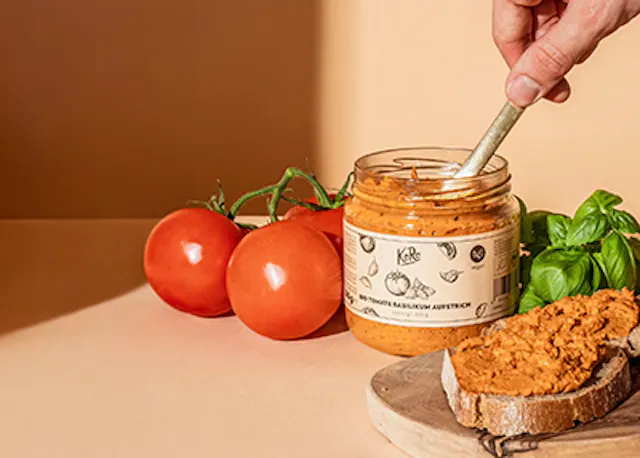 a person is dipping a piece of bread into a jar of tomato paste