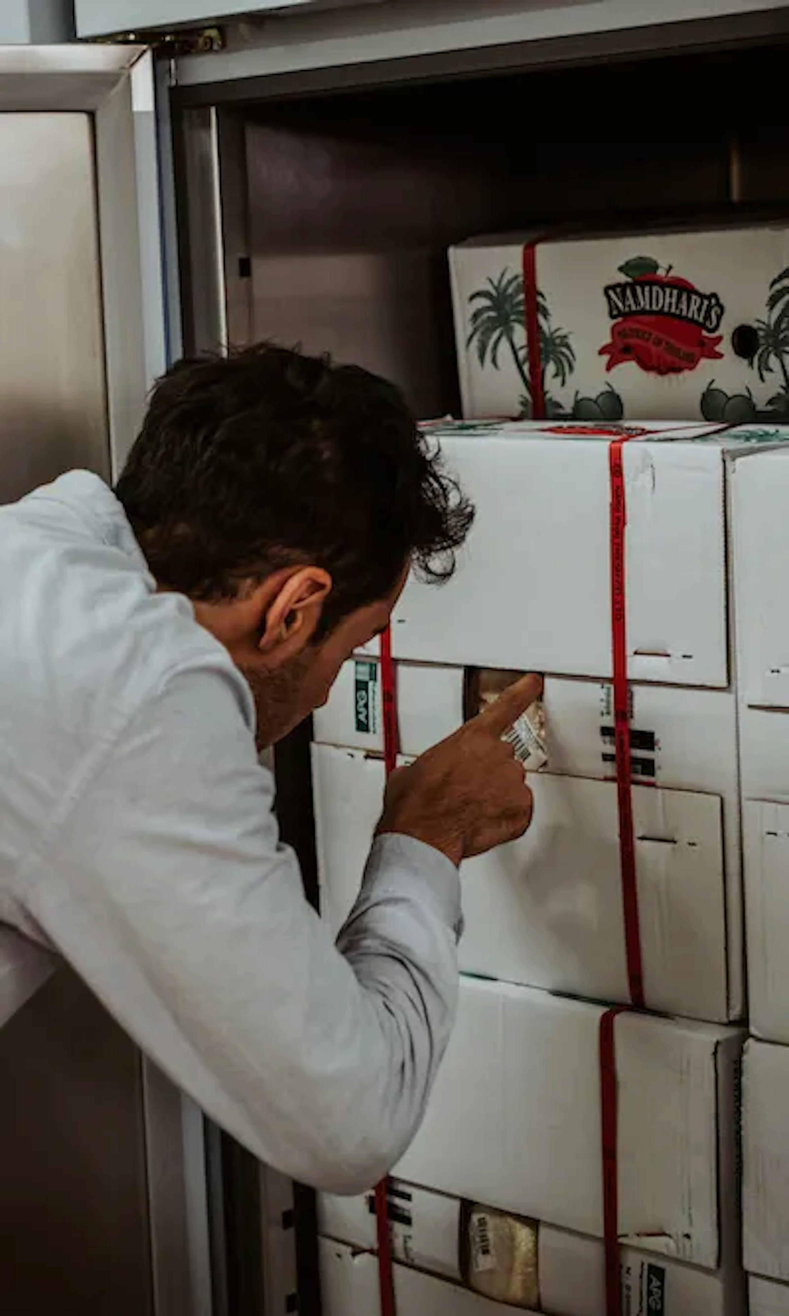 a man is reaching into a refrigerator filled with boxes of food .