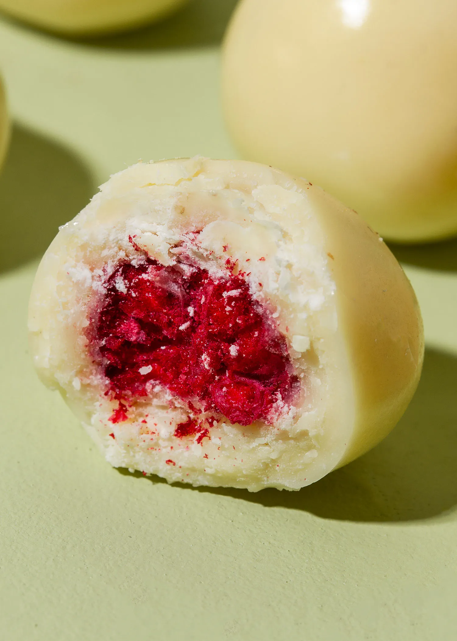un gros plan d' un bonbon blanc avec une framboise à l' intérieur