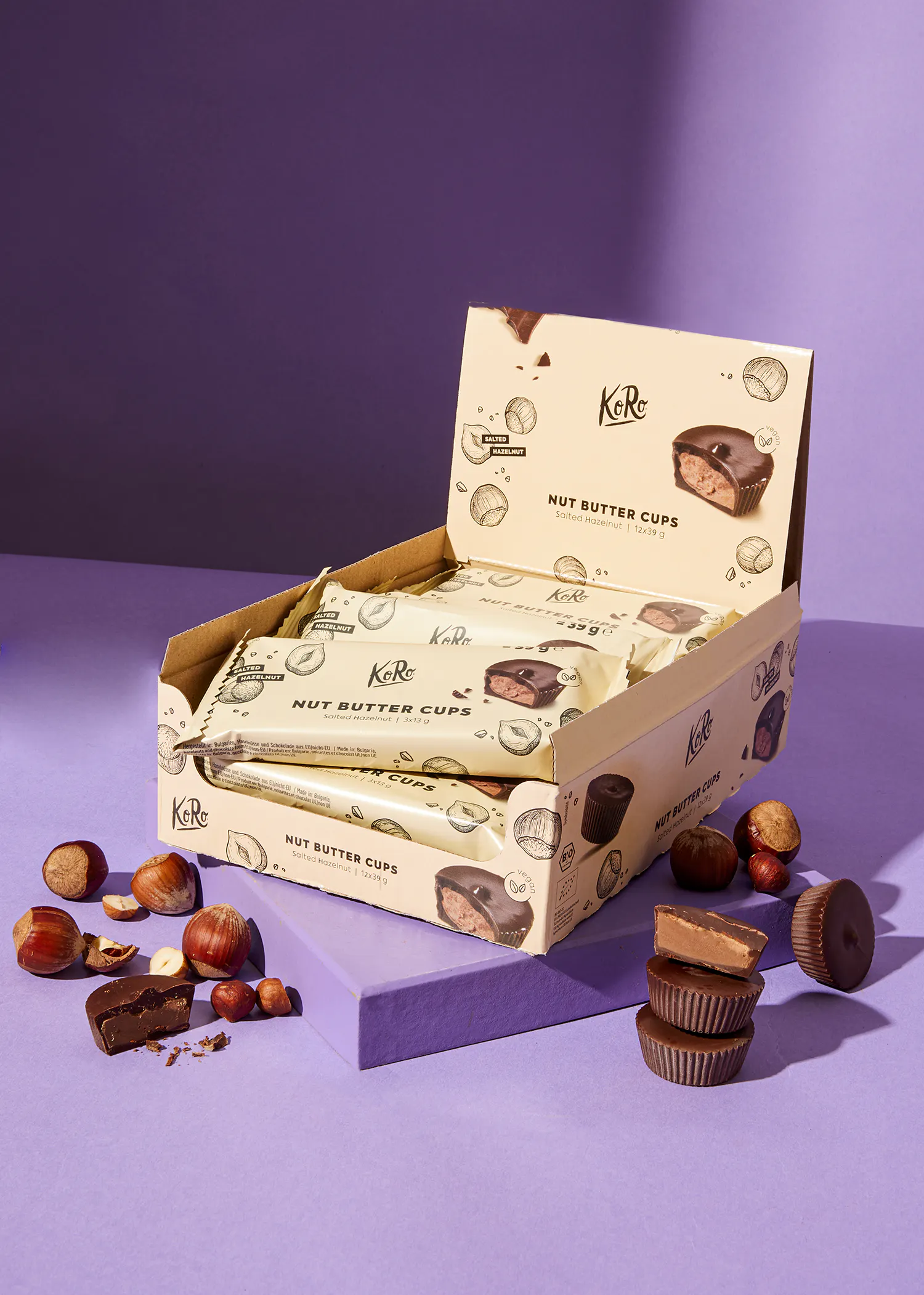 une boîte de tasses à beurre de noix avec des noisettes à côté