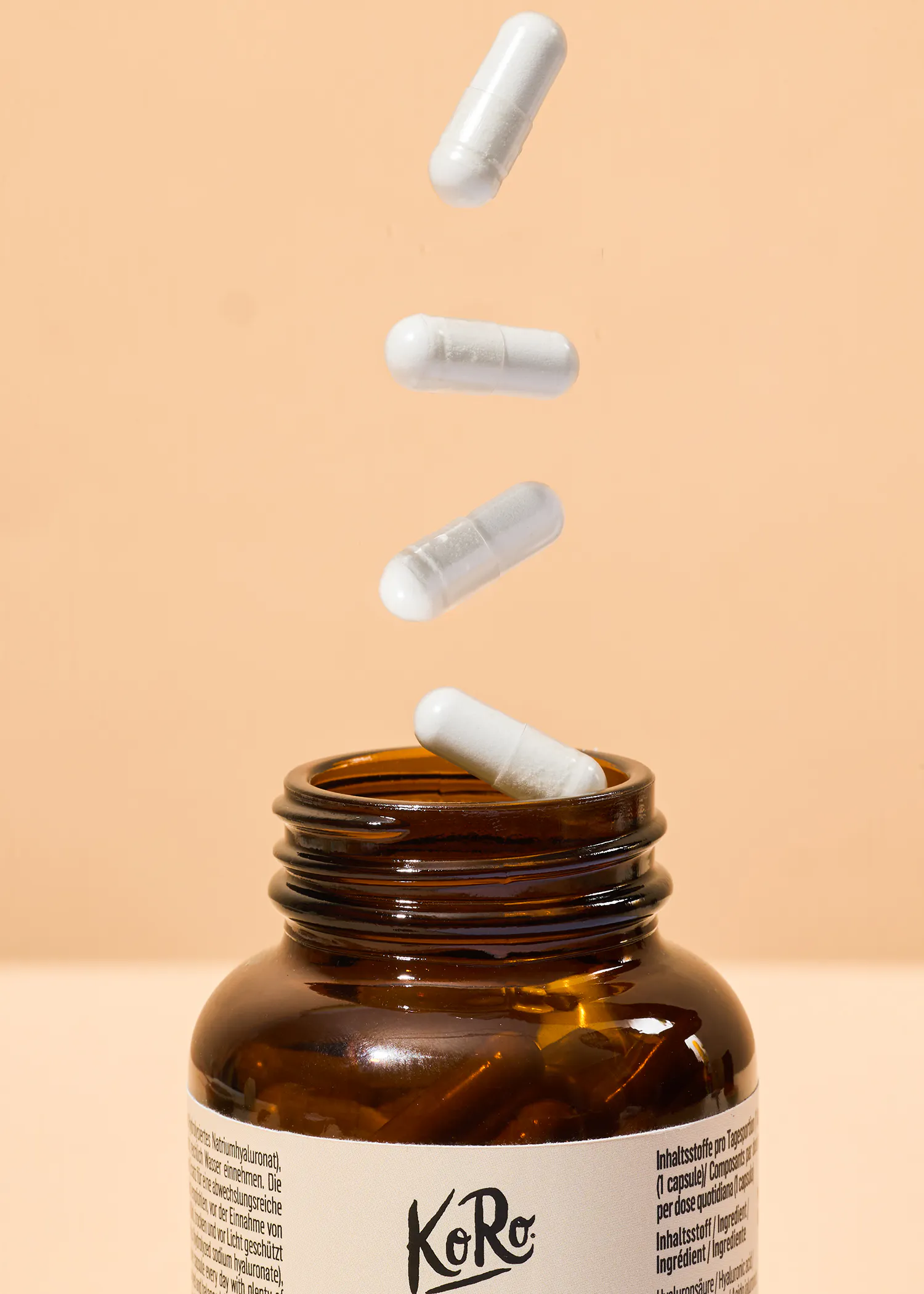 white capsules falling out of a bottle of koro