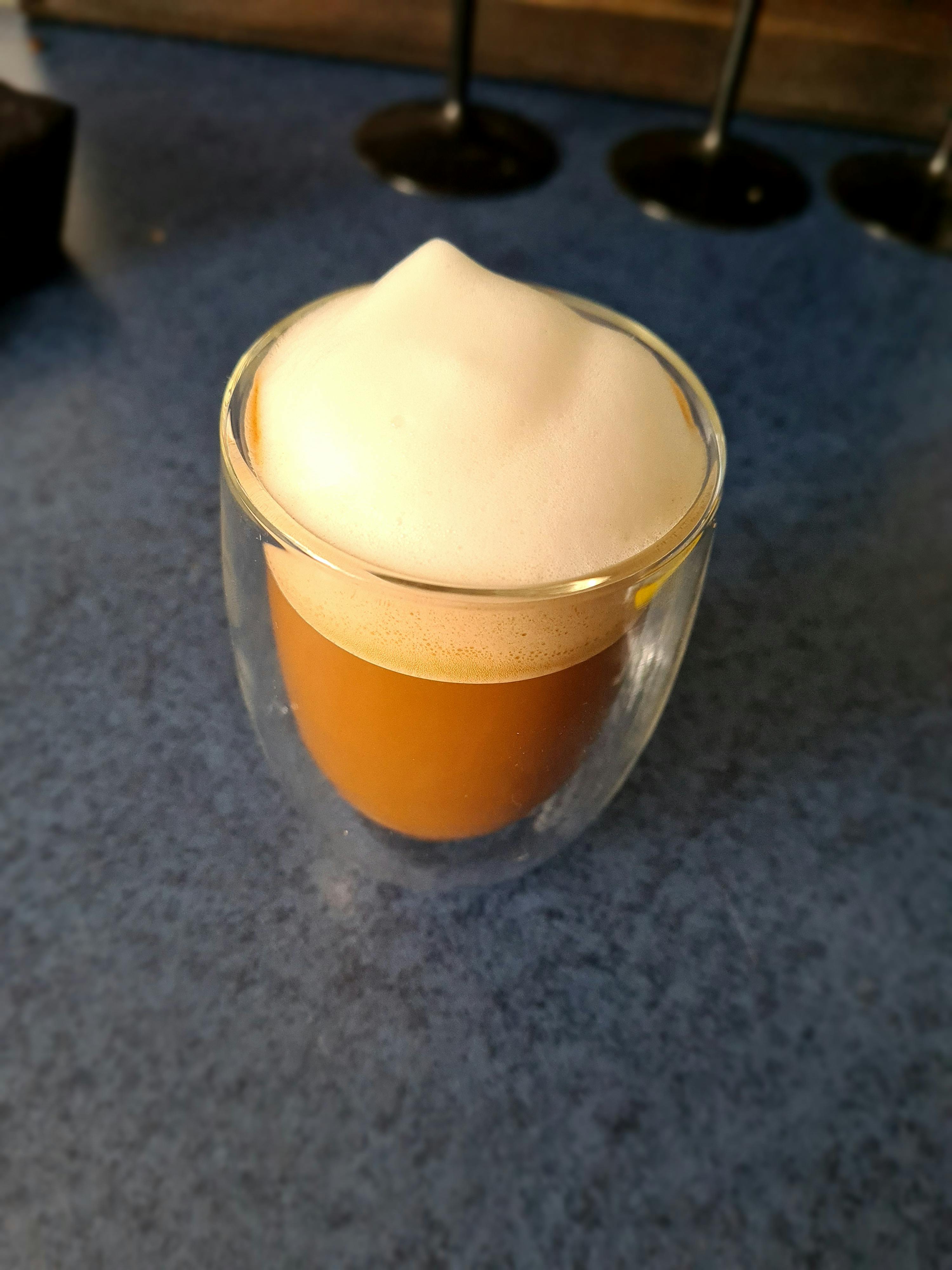 a close up of a cup of coffee with foam on top