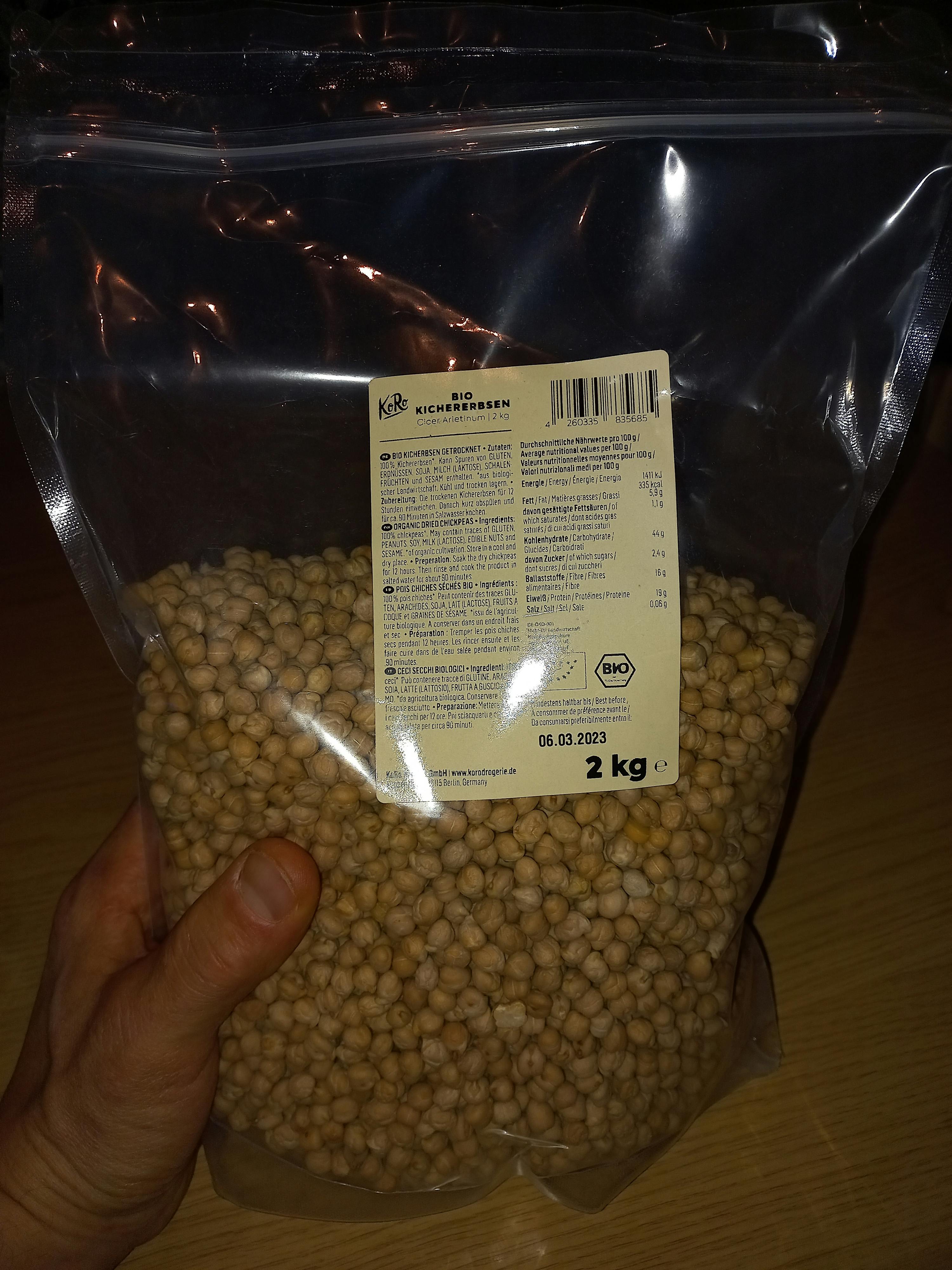 une personne tient un sac de pois chiches à 2 kg