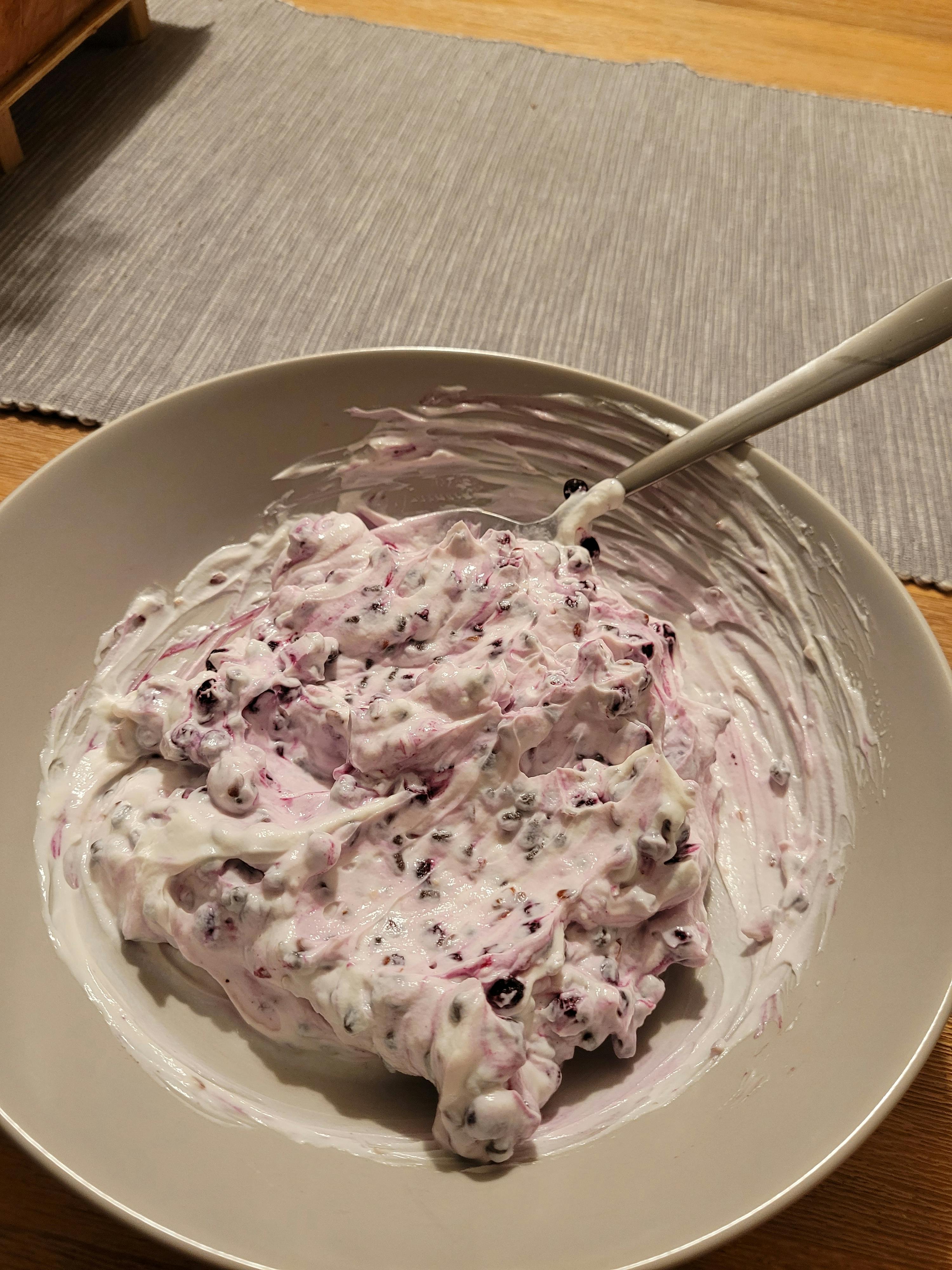 un bol de yaourt avec des myrtilles et une cuillère