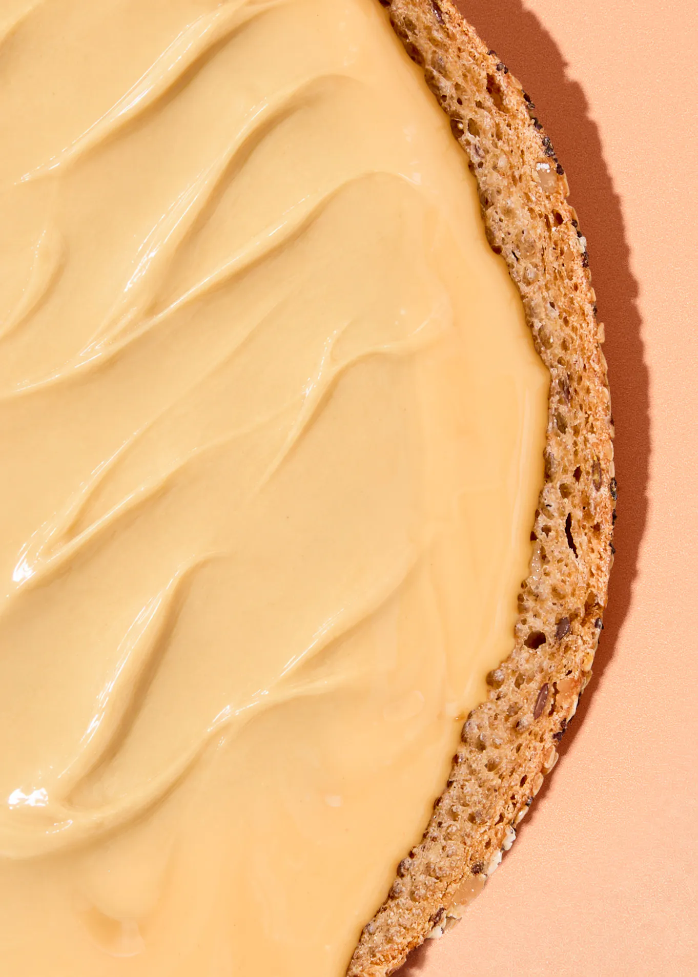 eine scheibe vollkornbrot, die dick mit einer cremigen, hellbraunen nussbutter bestrichen ist.