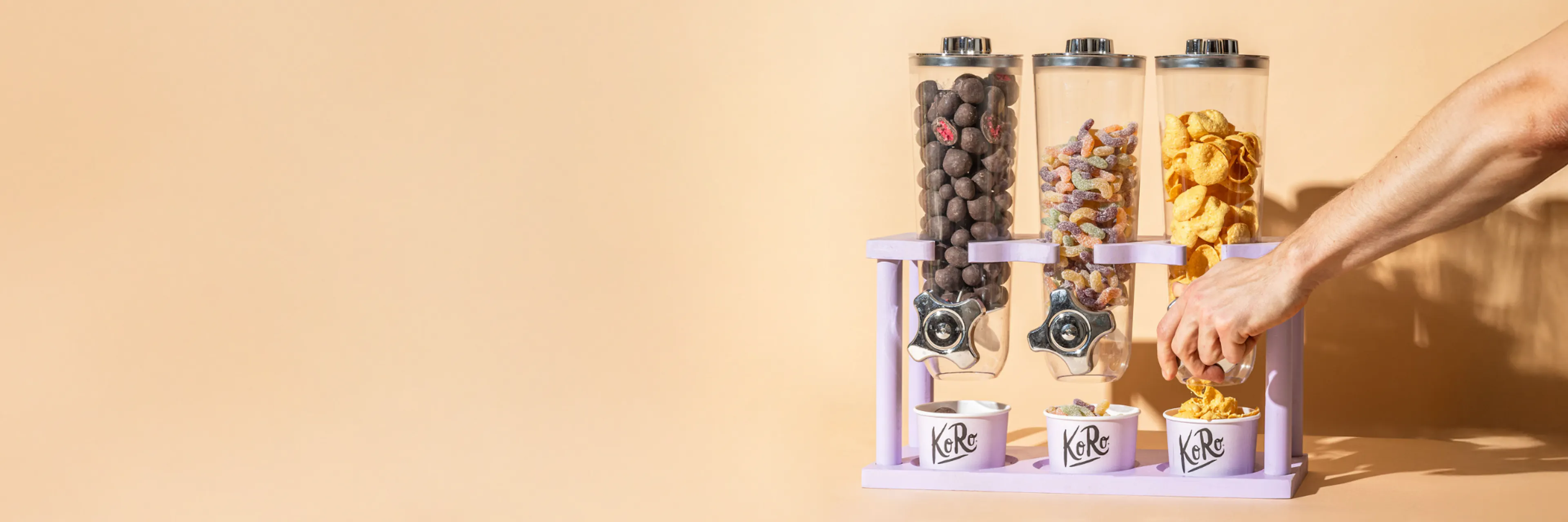 une personne verse du pop-corn dans un distributeur de pop-corn violet