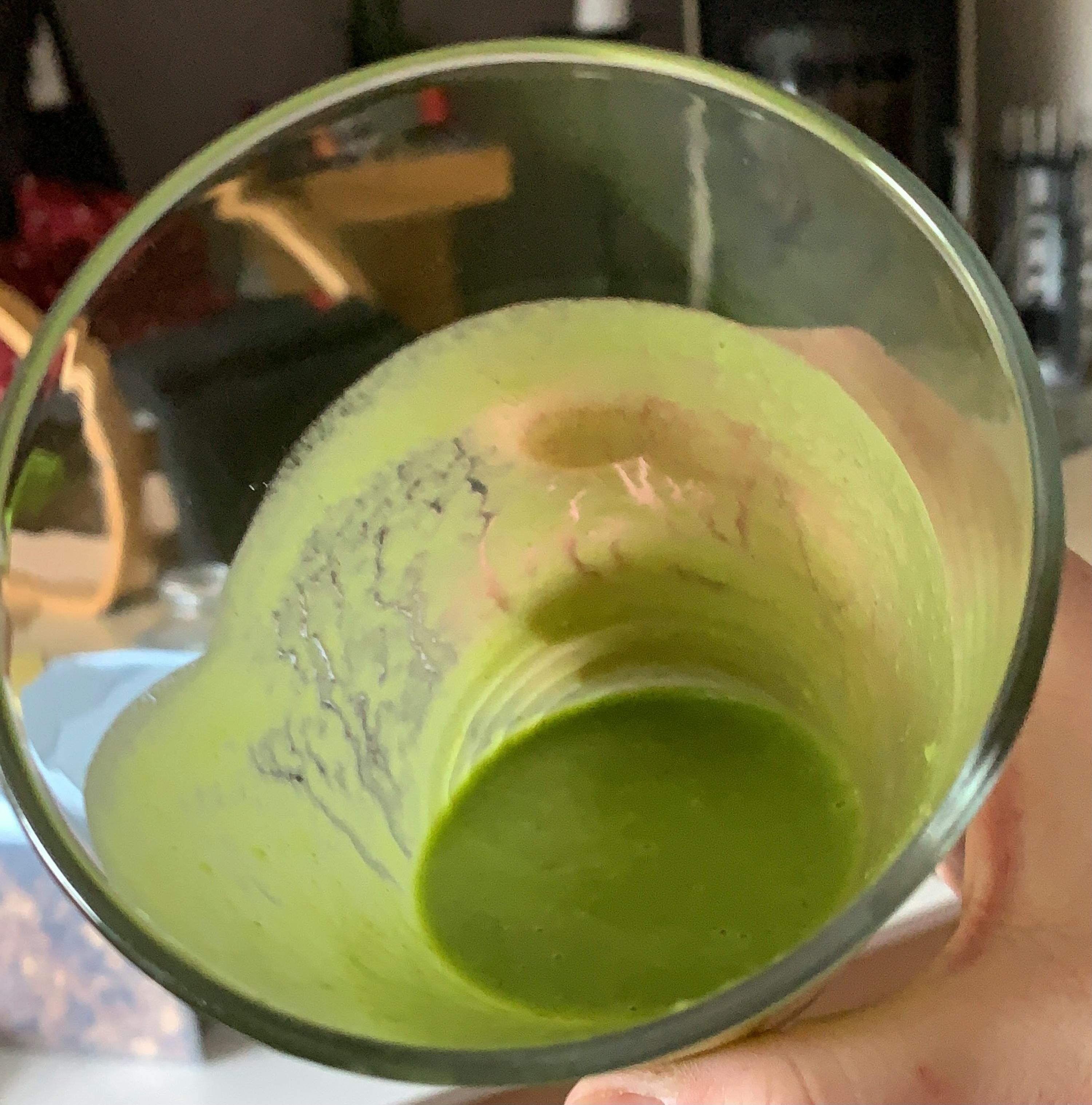 eine Person hält ein Glas mit einem grünen Getränk darin