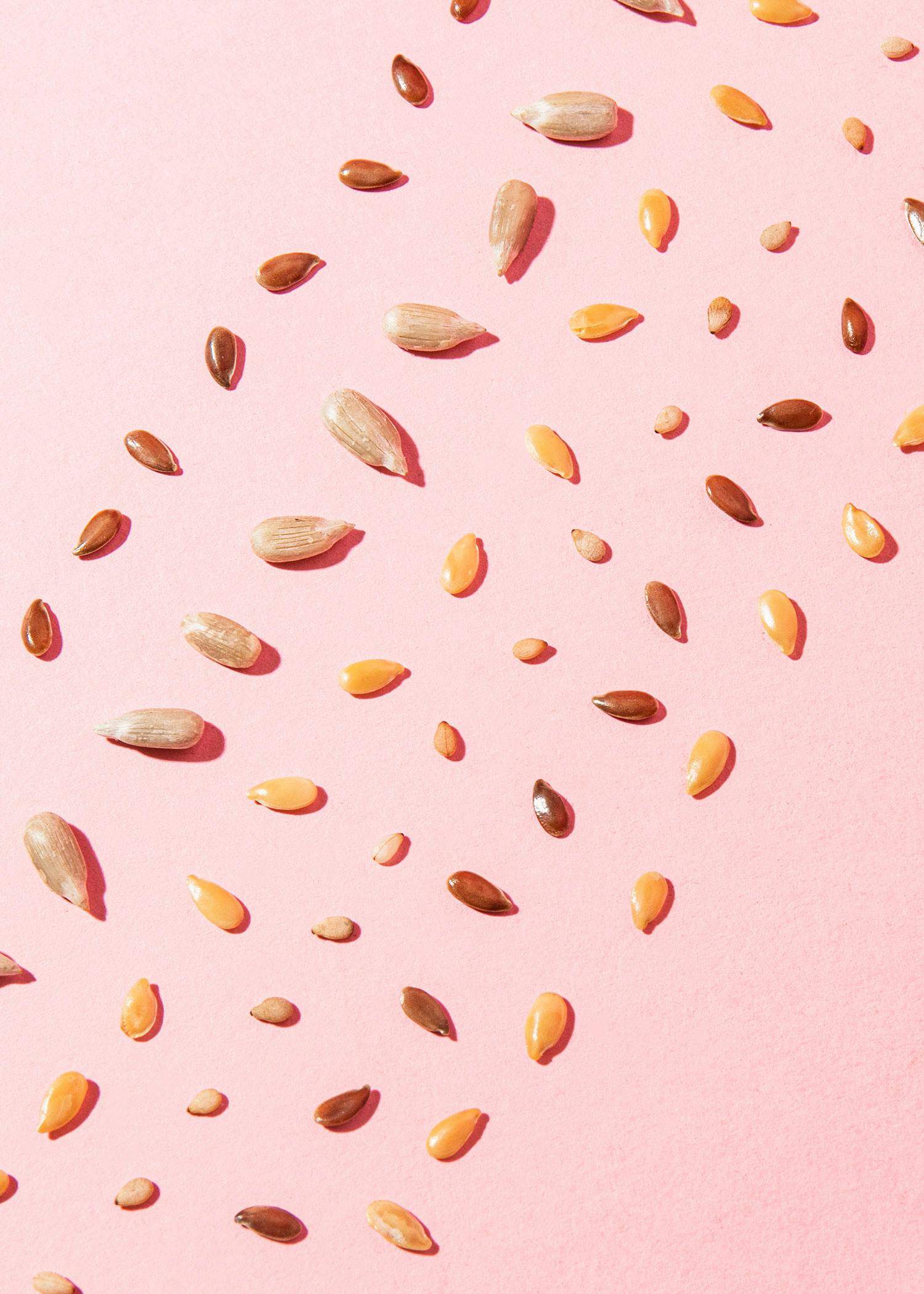 verschiedene Sonnenblumenkerne auf einem rosa Hintergrund