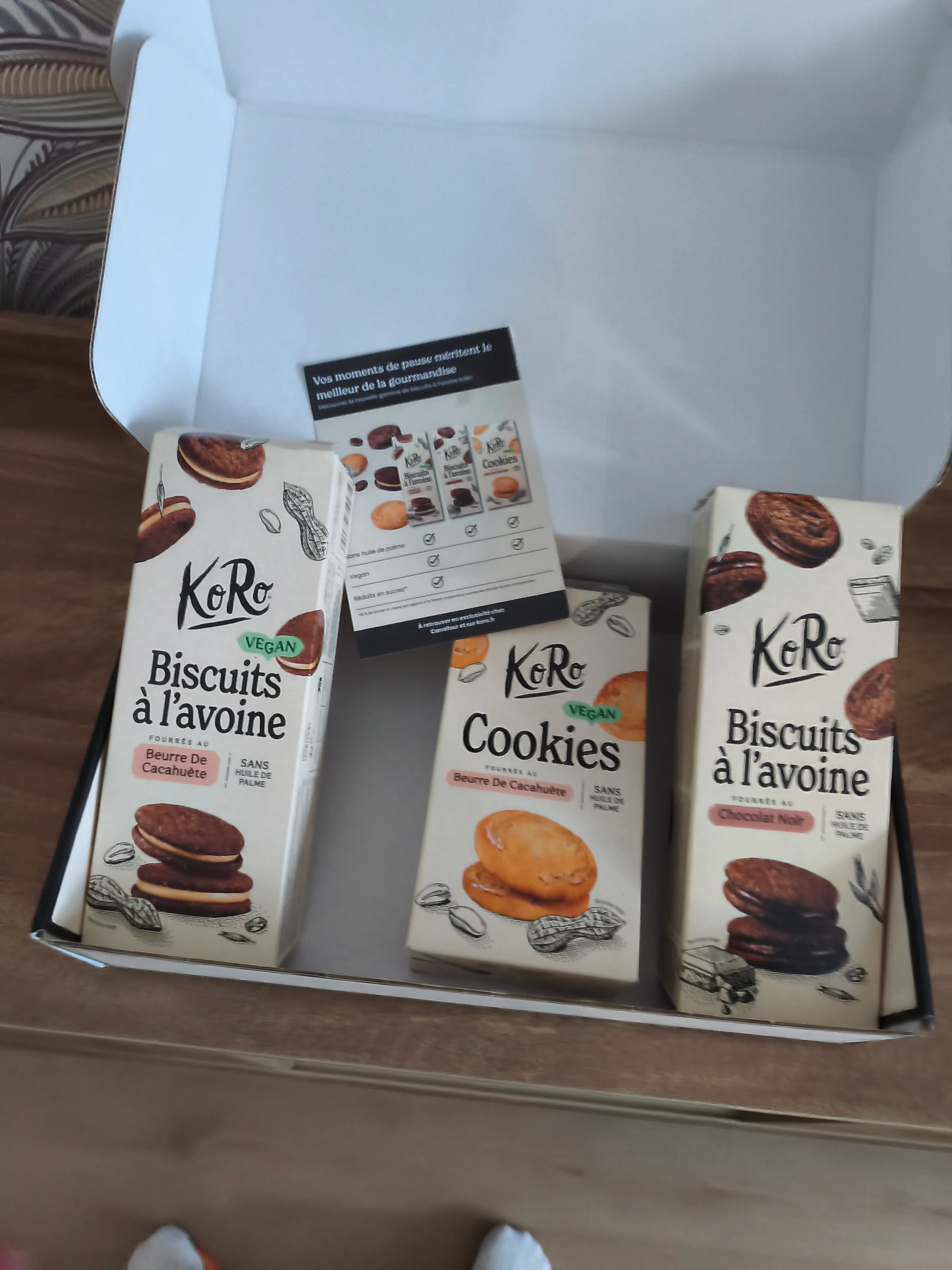 an open box containing three packages of koro vegan cookies and a promotional flyer.