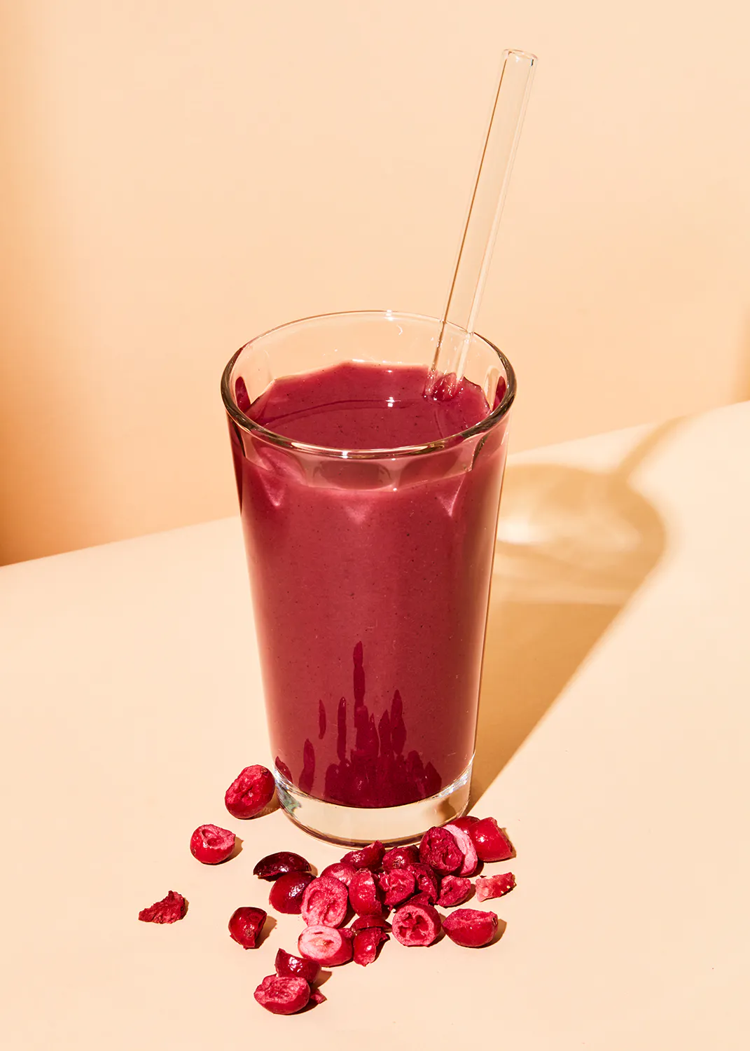 un verre de smoothie avec une paille et des canneberges