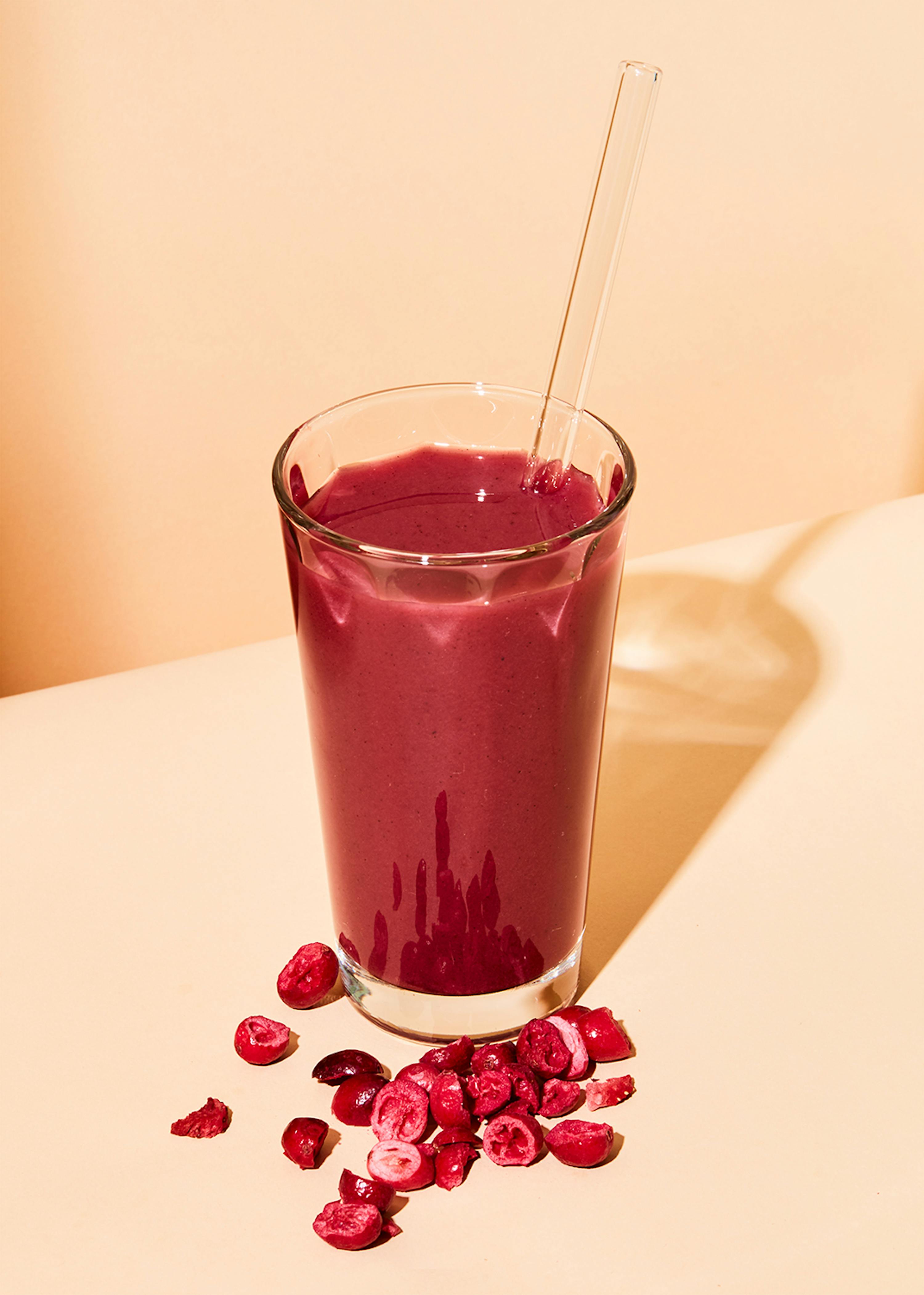 a glass of cranberry juice with a clear straw