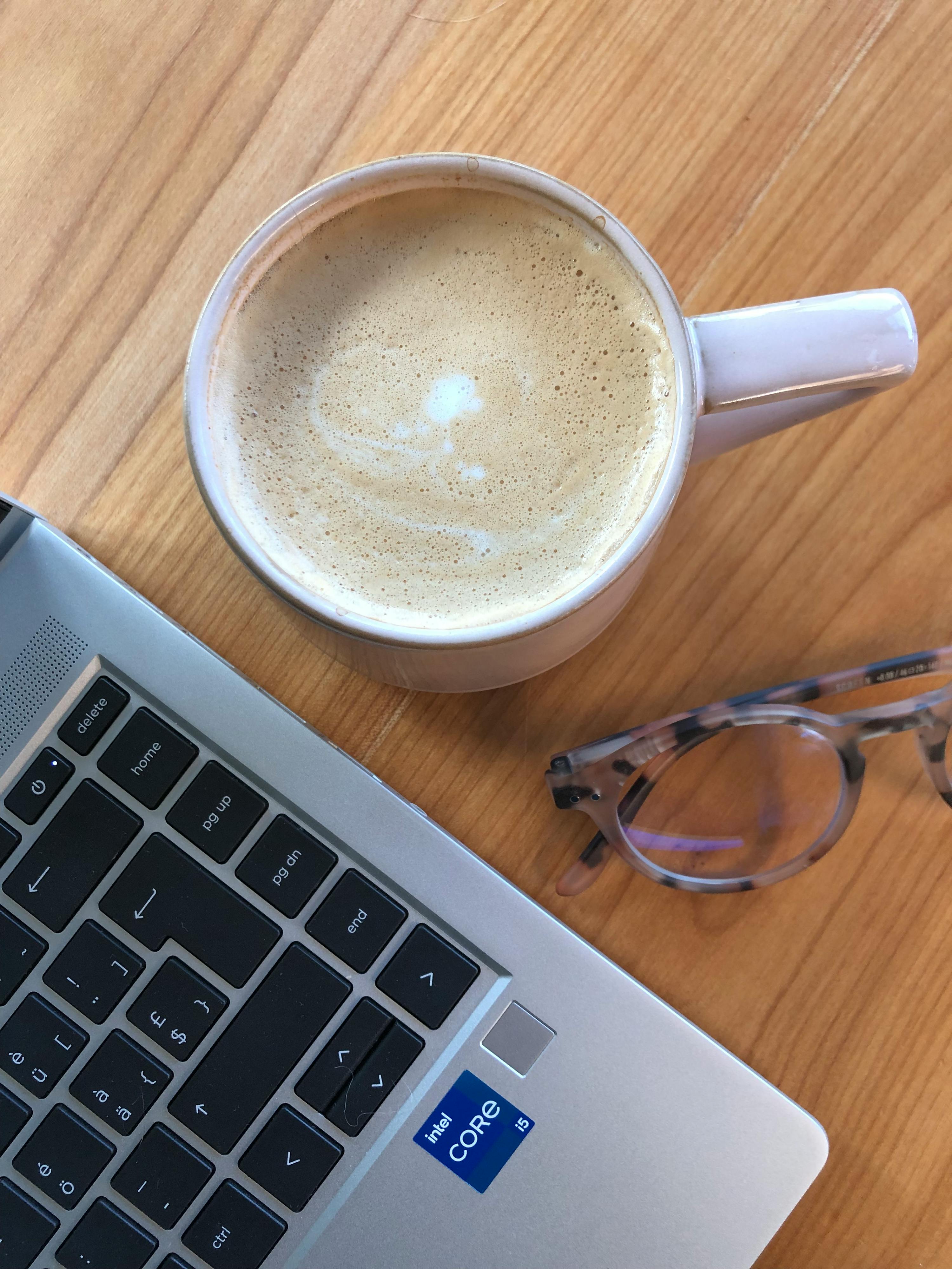 une tasse de café est assise à côté d' un ordinateur portable avec une étiquette intel core