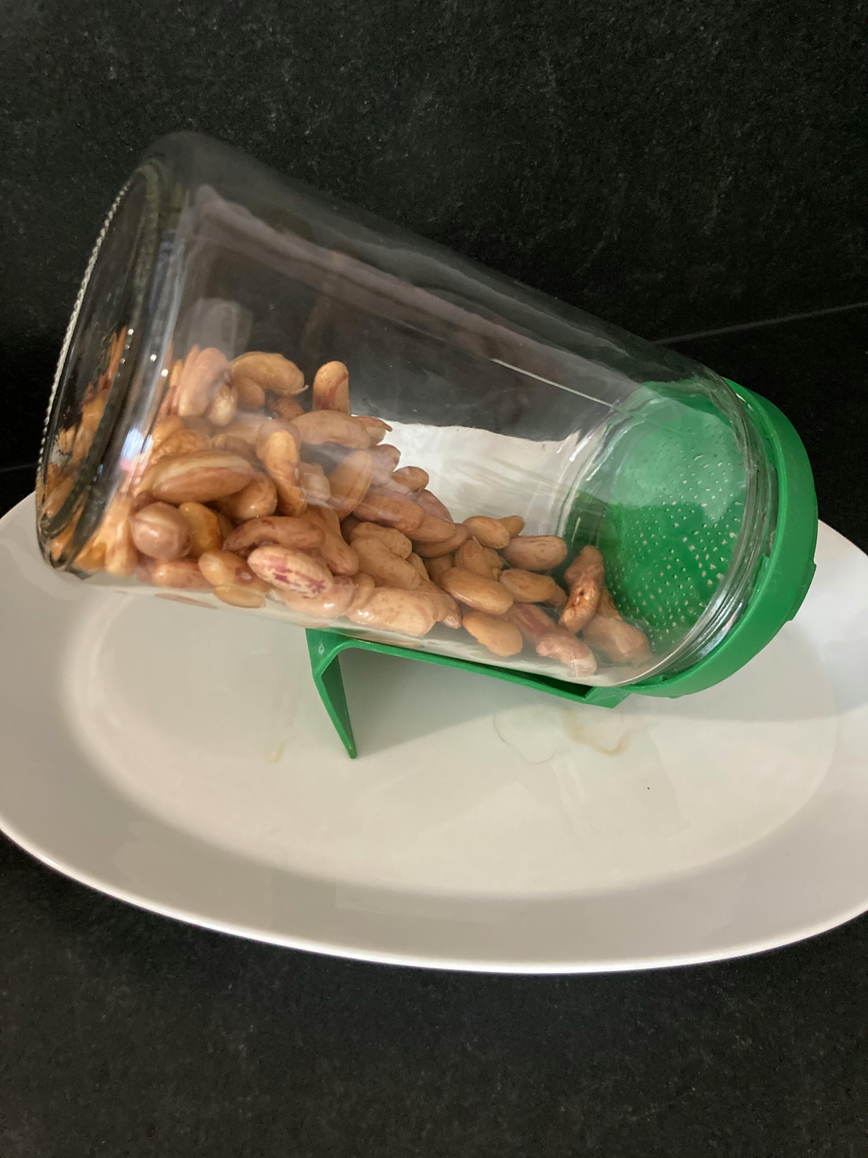 un barattolo di vetro pieno di mandorle su un piatto bianco