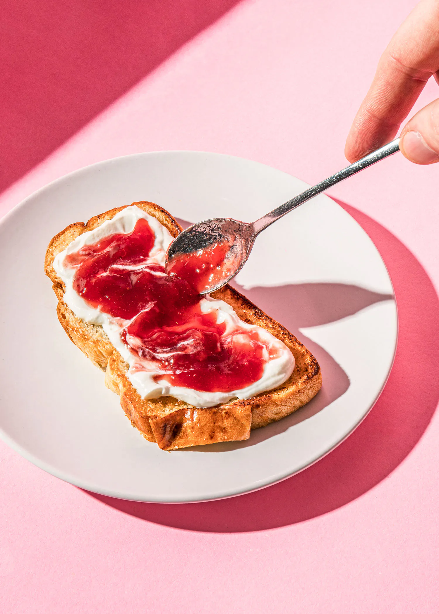 une personne verse de la confiture sur une tranche de pain grillé