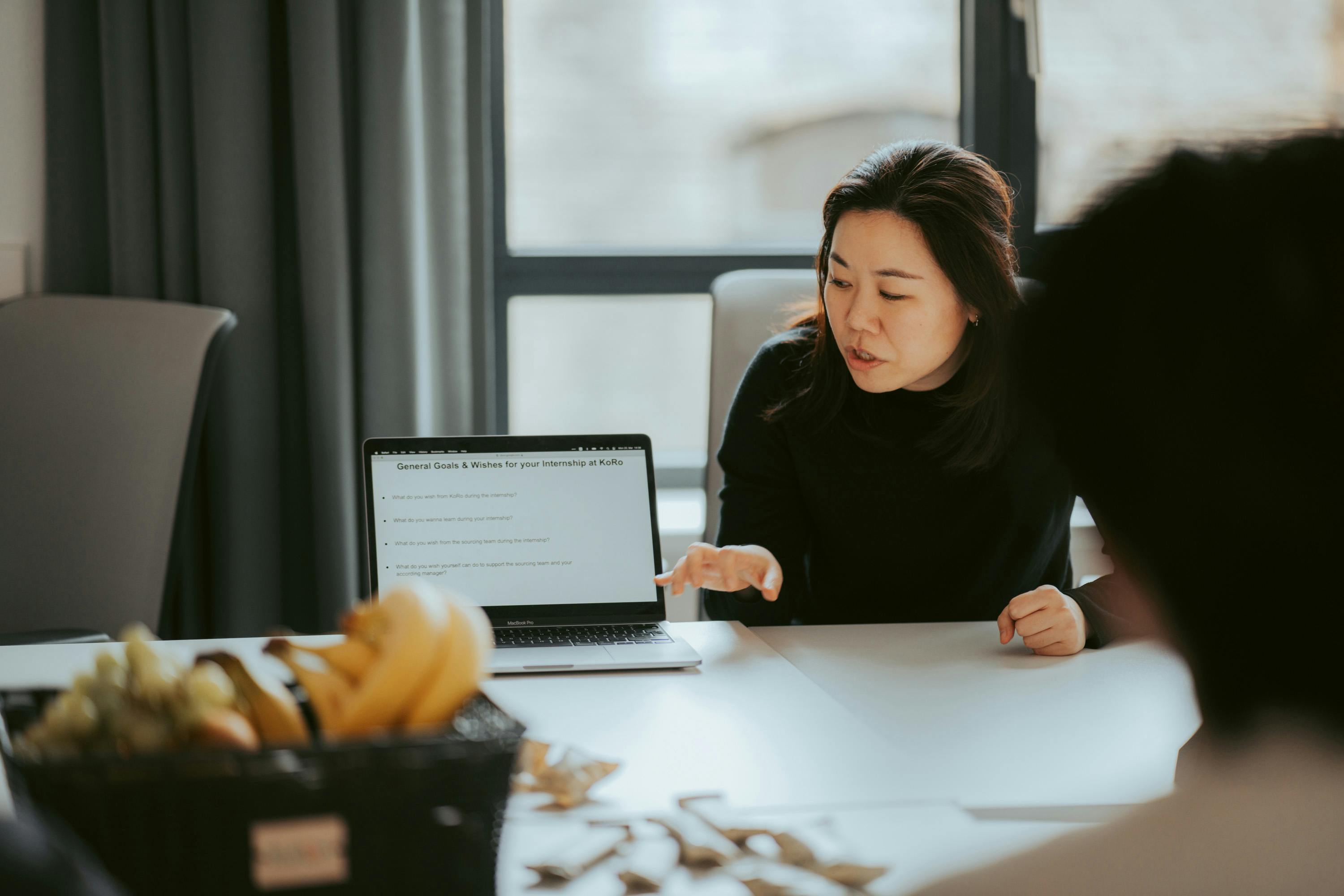 a woman sits at a table looking at a laptop that says general costs & allowances for your inventory on it