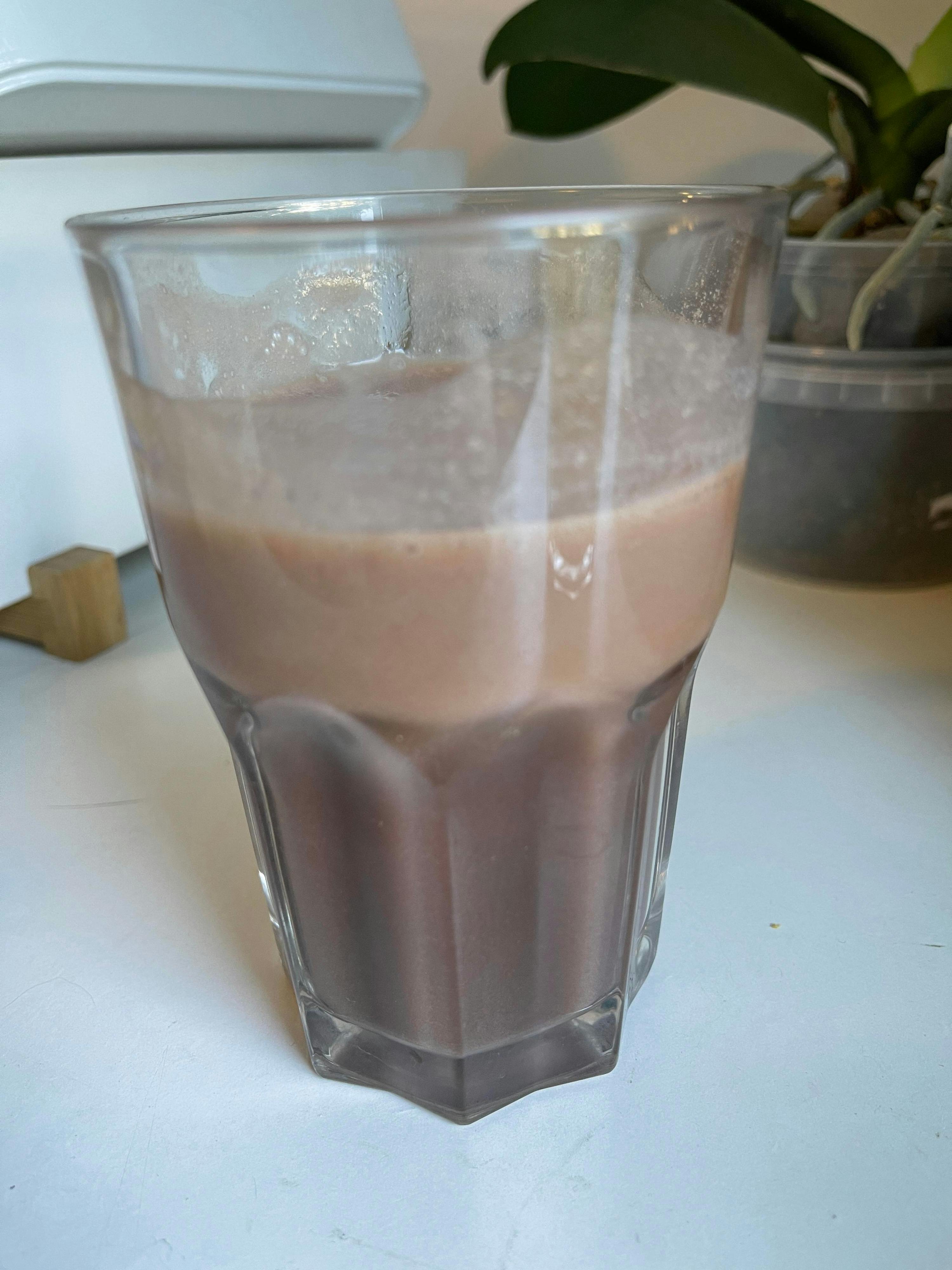 a glass filled with a brown liquid on a table