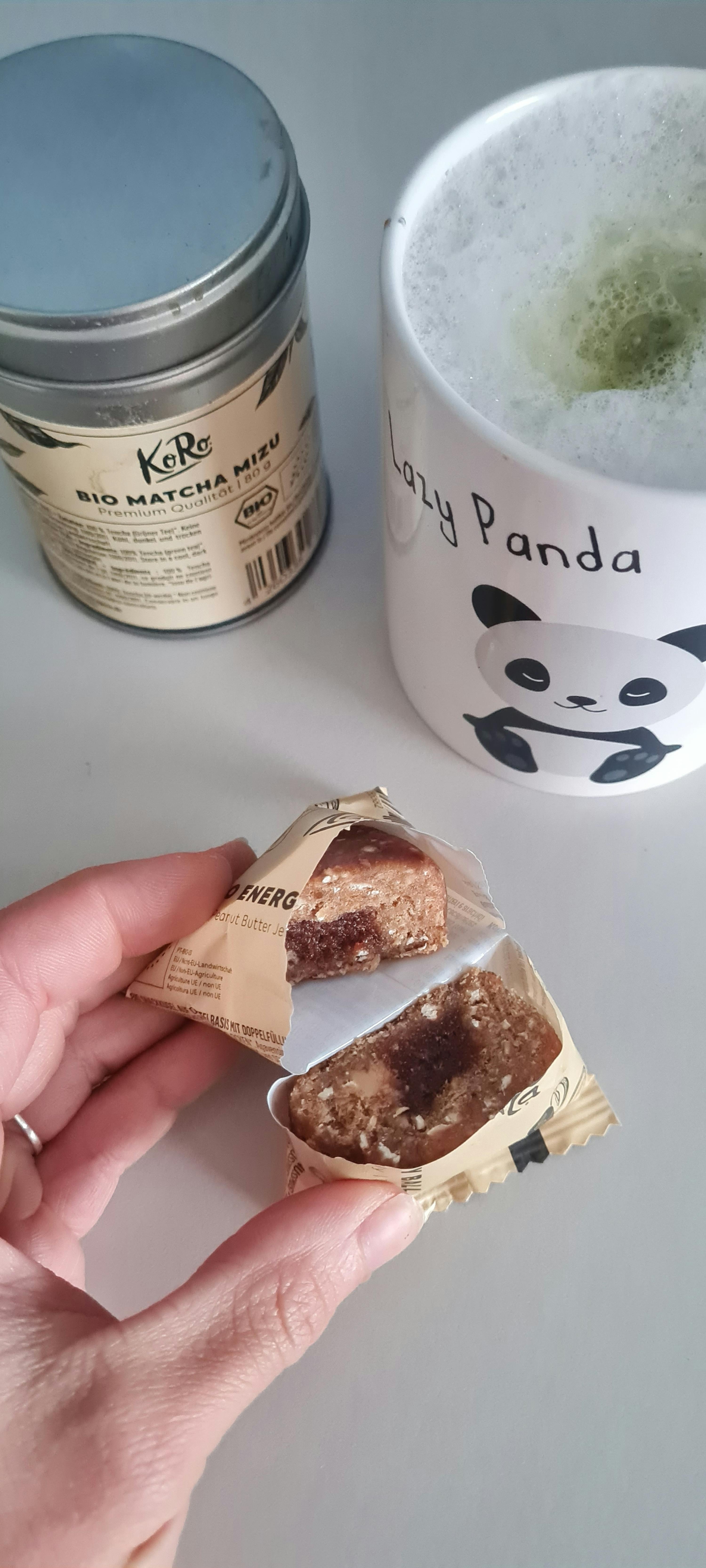 una persona tiene in mano una barretta di cibo e una tazza di latte